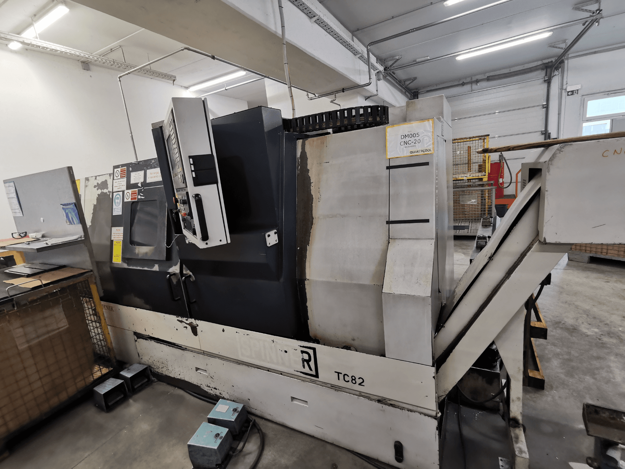 CNC machine, merk Spinner, model TC82, zijaanzicht met bedieningspaneel en afvalgoot in een werkplaats.