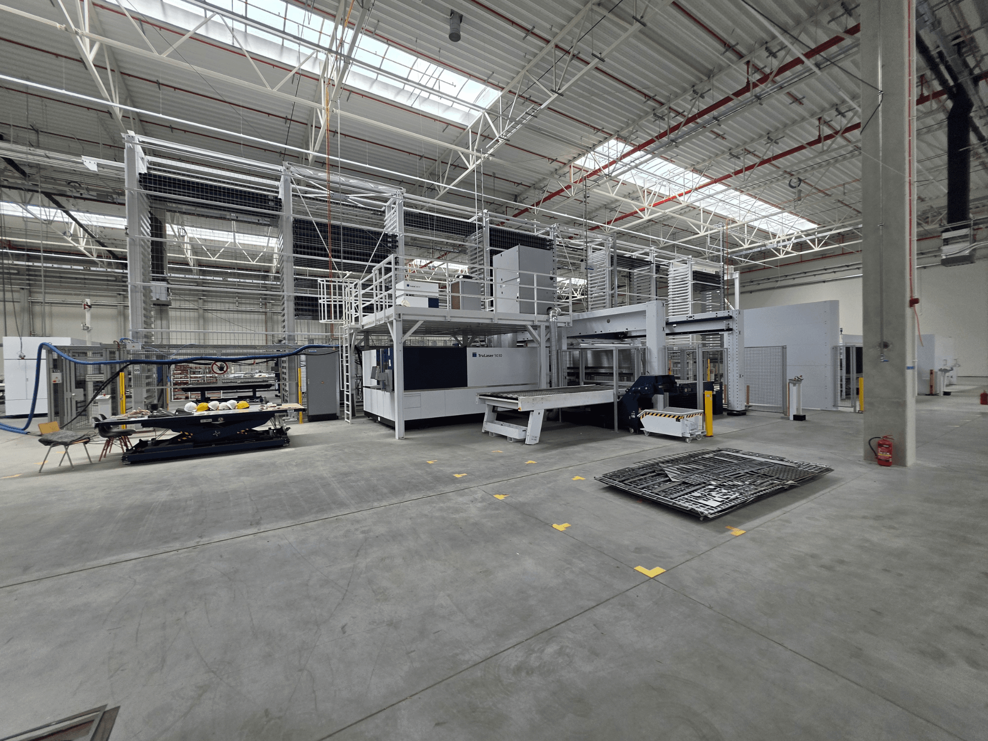 TRUMPF geautomatiseerd productiesysteem voor plaatbewerking, zijaanzicht met machines, werkruimte en gereedschappen in een grote industriële omgeving.
