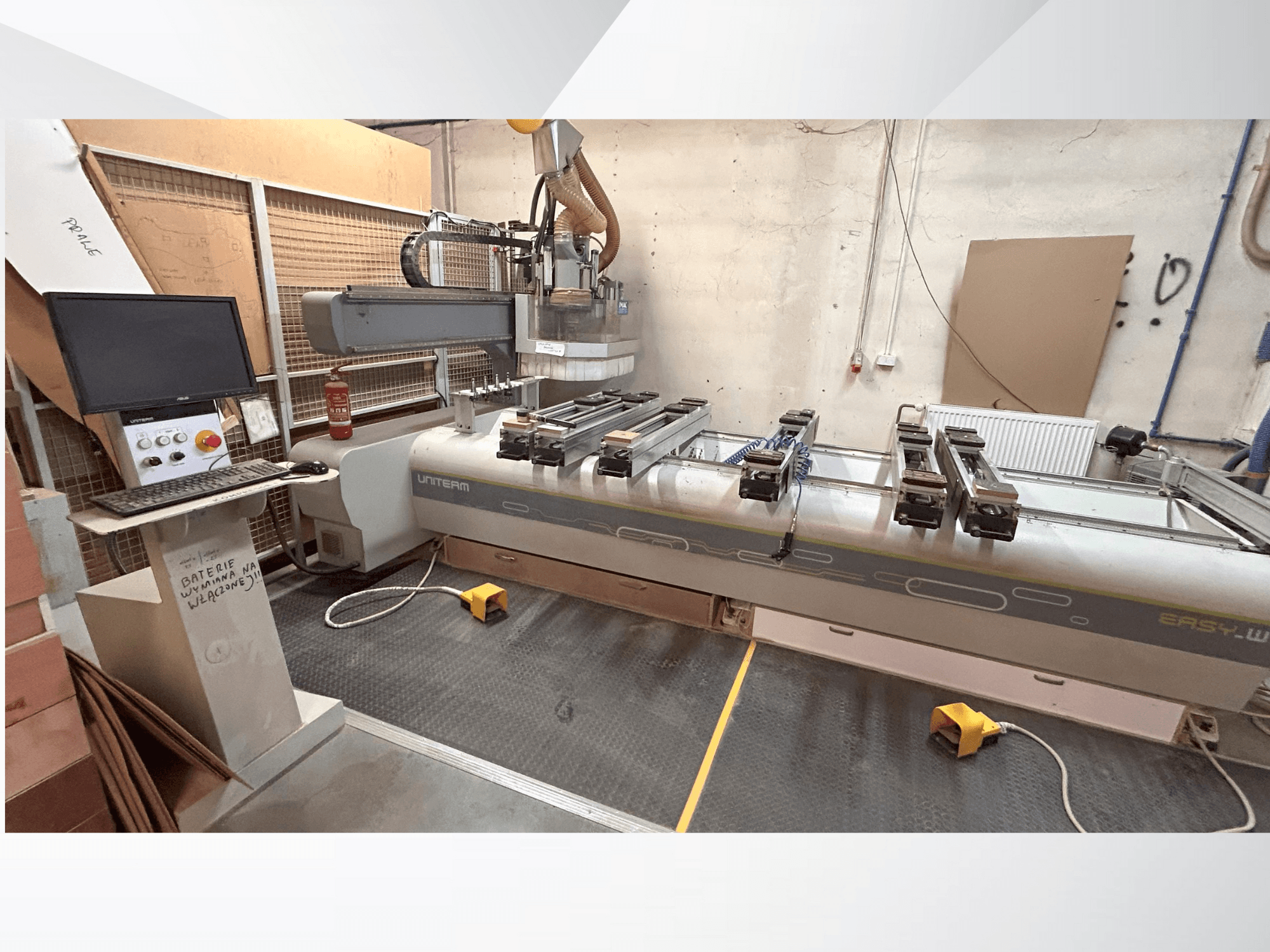 Vooraanzicht van een UNITEM EASY-W CNC machine, met een bedieningspaneel, monitor en opgespannen werkstukken op de werktafel.