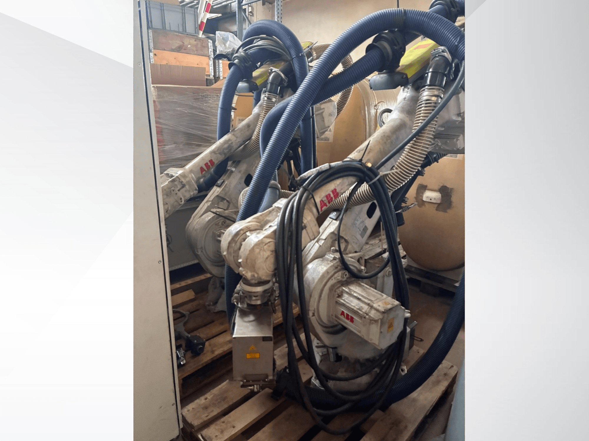 ABB IRB 4600-40/2.55-robotarm, zijaanzicht met dubbele armen en aangesloten slangen, gemonteerd op pallets in een magazijnomgeving.