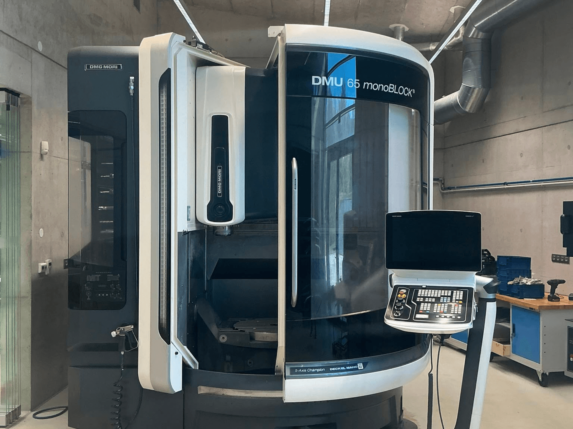 DMG MORI DMU 65 monoBLOCK verticaal bewerkingscentrum, vooraanzicht, met weergave van het bedieningspaneel en machineonderdelen in een werkplaatsomgeving.