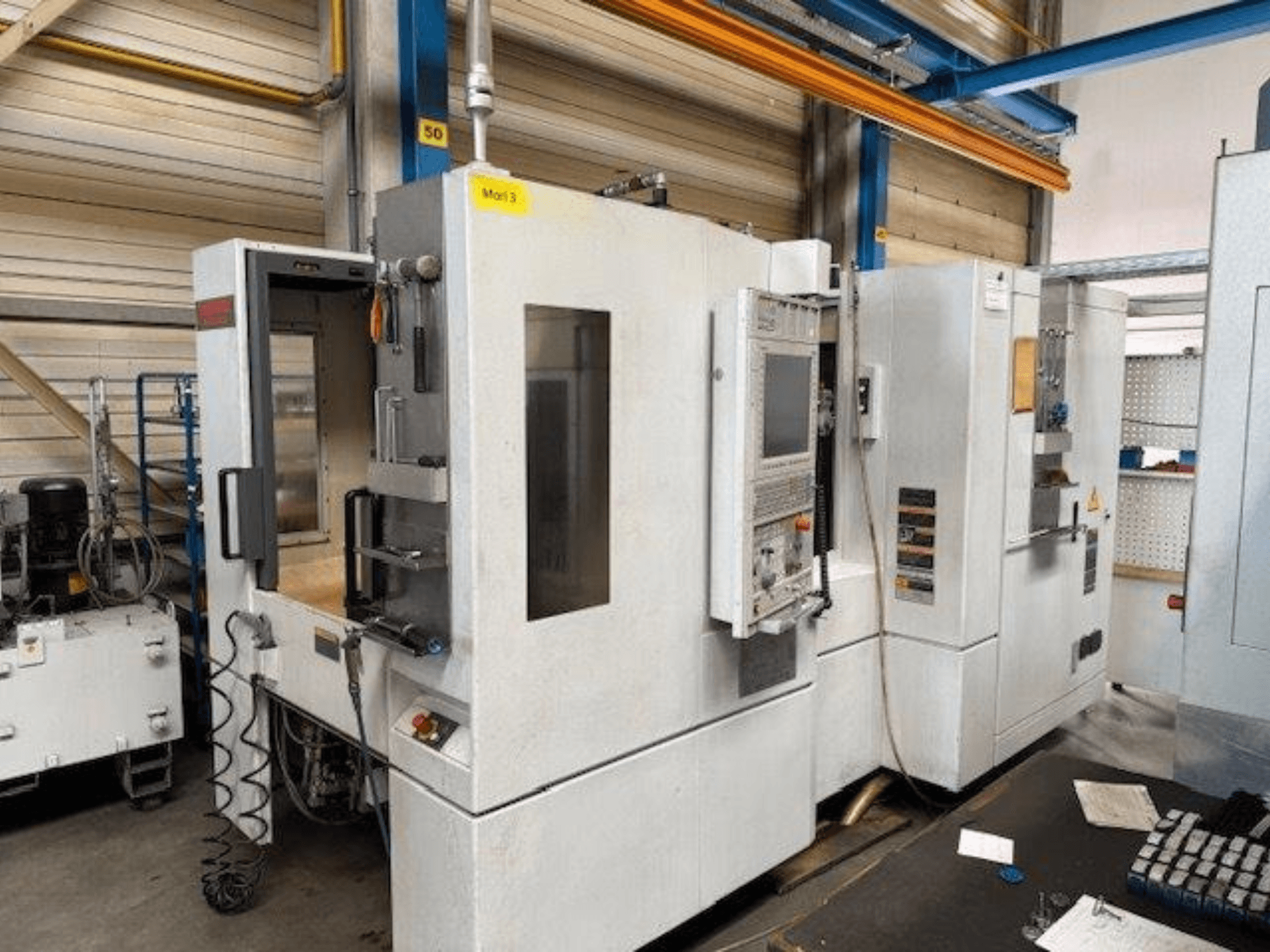 Vooraanzicht van een MORI SEIKI NH4000 DCG horizontaal bewerkingscentrum met geopende deur en zichtbaar bedieningspaneel, waarop de werkruimte te zien is.
