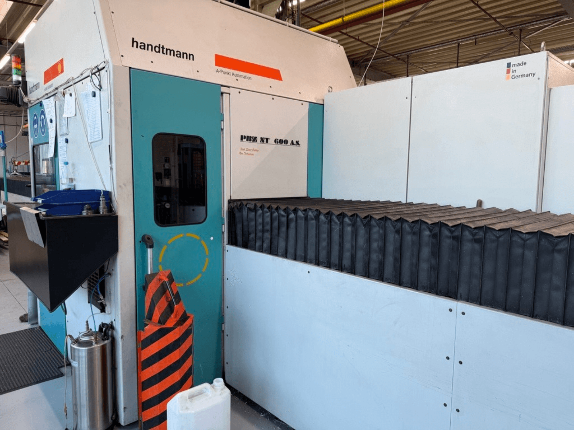 Vooraanzicht van de Handtmann PBZ NT 600 AS portaalfreesmachine, met een donker werkoppervlak en veiligheidsbarrières.