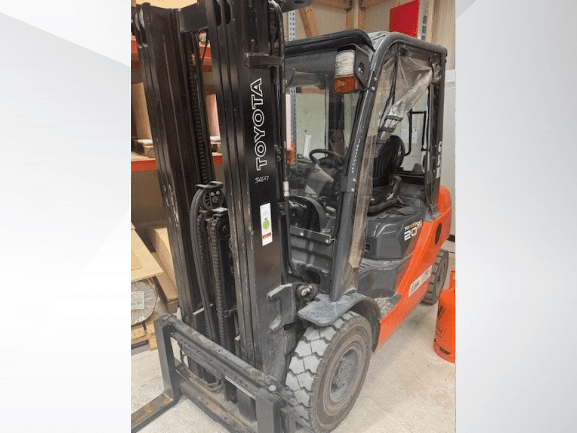 Toyota 20 vorkheftruck gezien vanaf de voorkant, met een zwarte mast, transparante cabine en oranje propaantank ernaast.