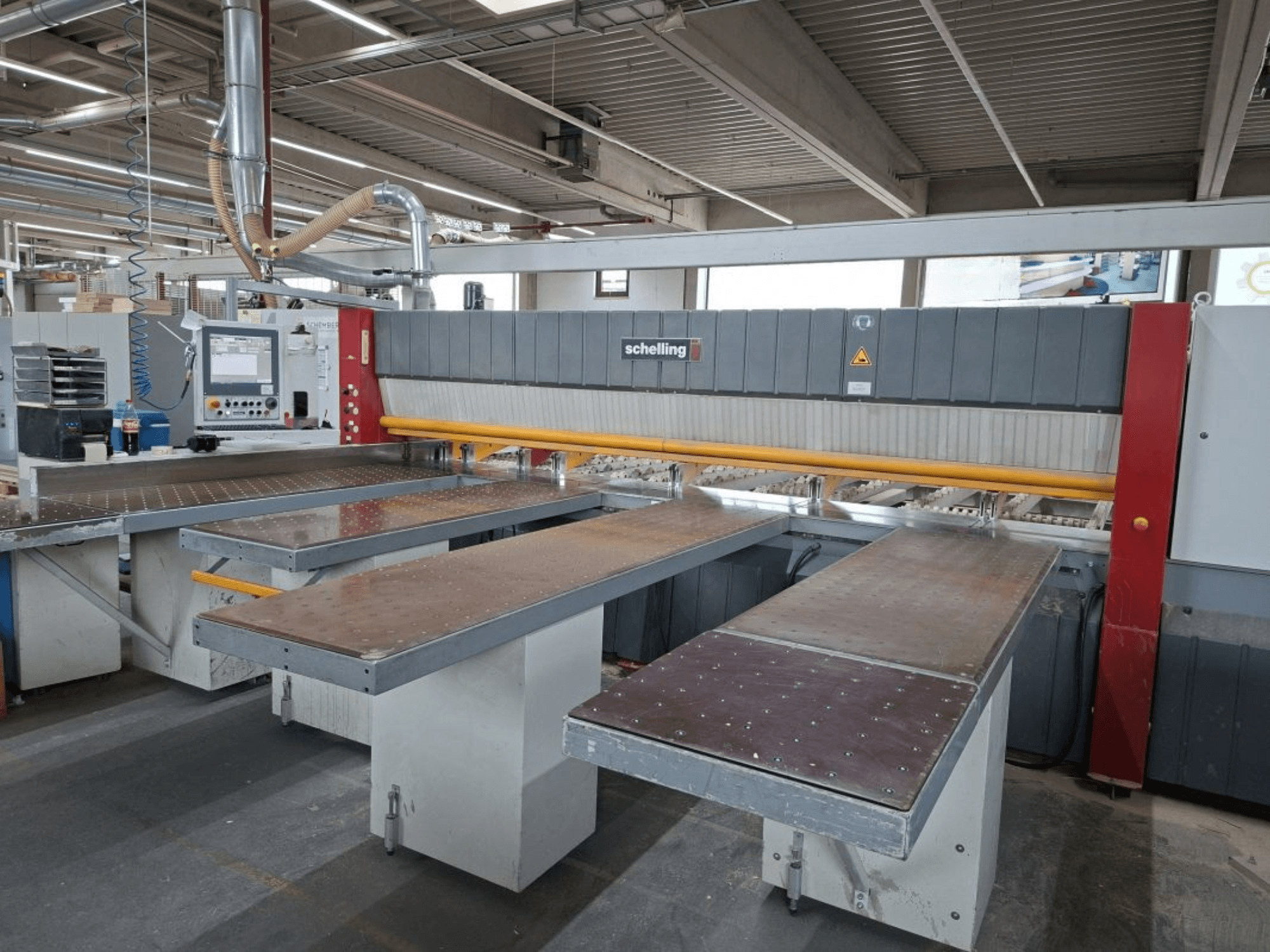 Wandzaag SCHELLING FH 4 in werkplaats, met twee verlengde tafels en bedieningspaneel. Vooraanzicht accentueert de operationele setup.