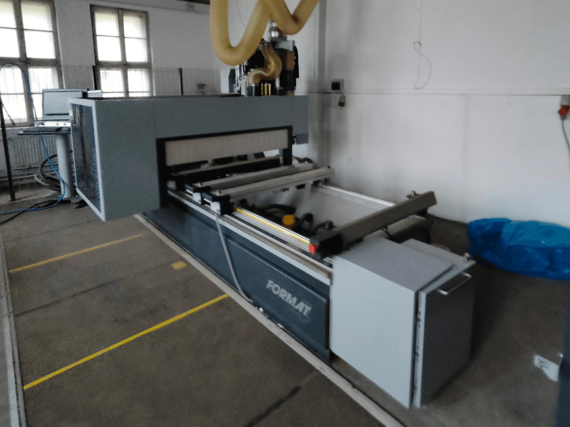 Vooraanzicht van een Format CNC machine met een grijze behuizing, geleiderails en een zichtbaar bedieningspaneel.