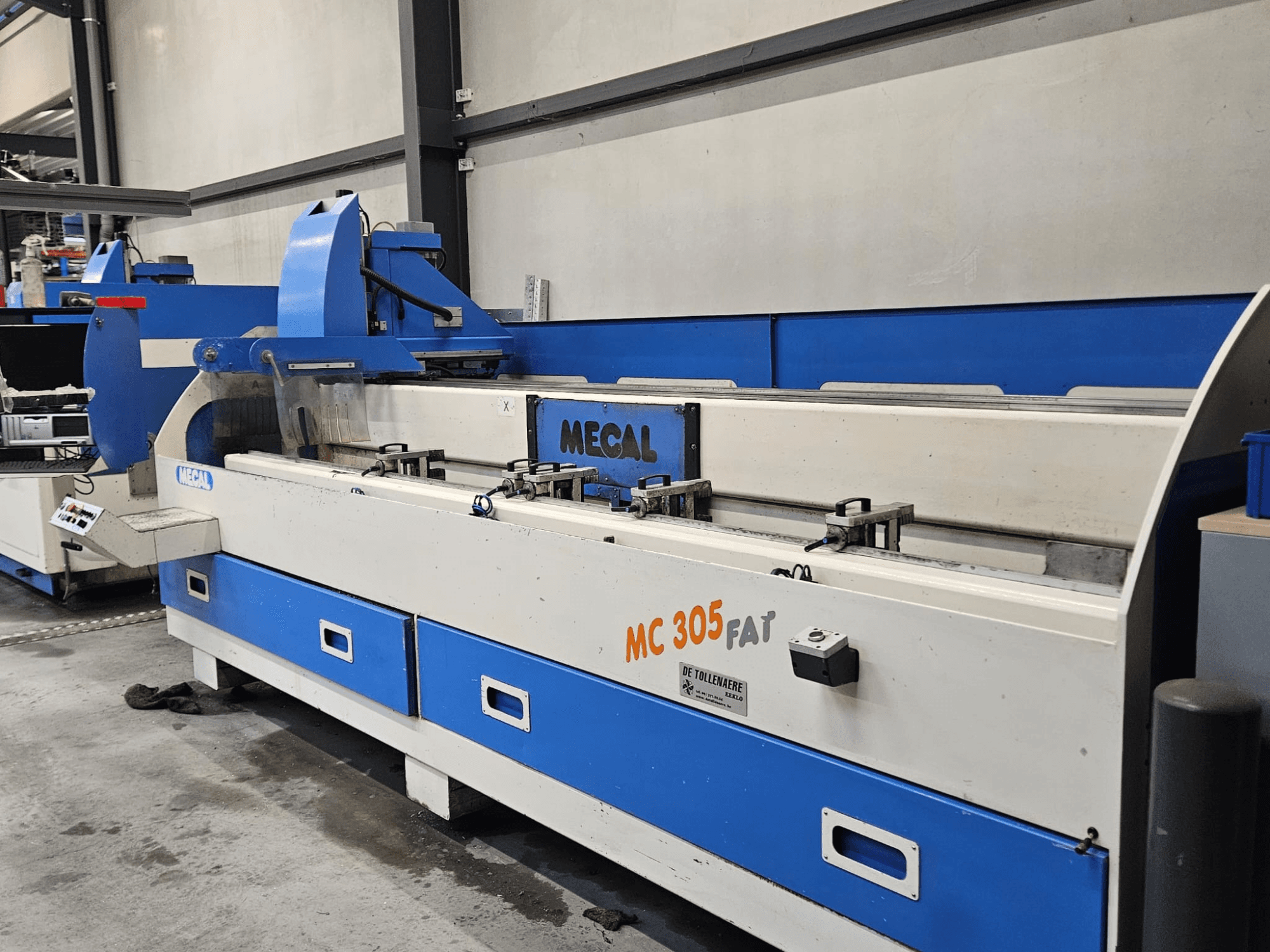 MECAL MC 305 FAT machine in een fabrieksomgeving, vooraanzicht met de bedieningselementen en blauw-wit ontwerp.