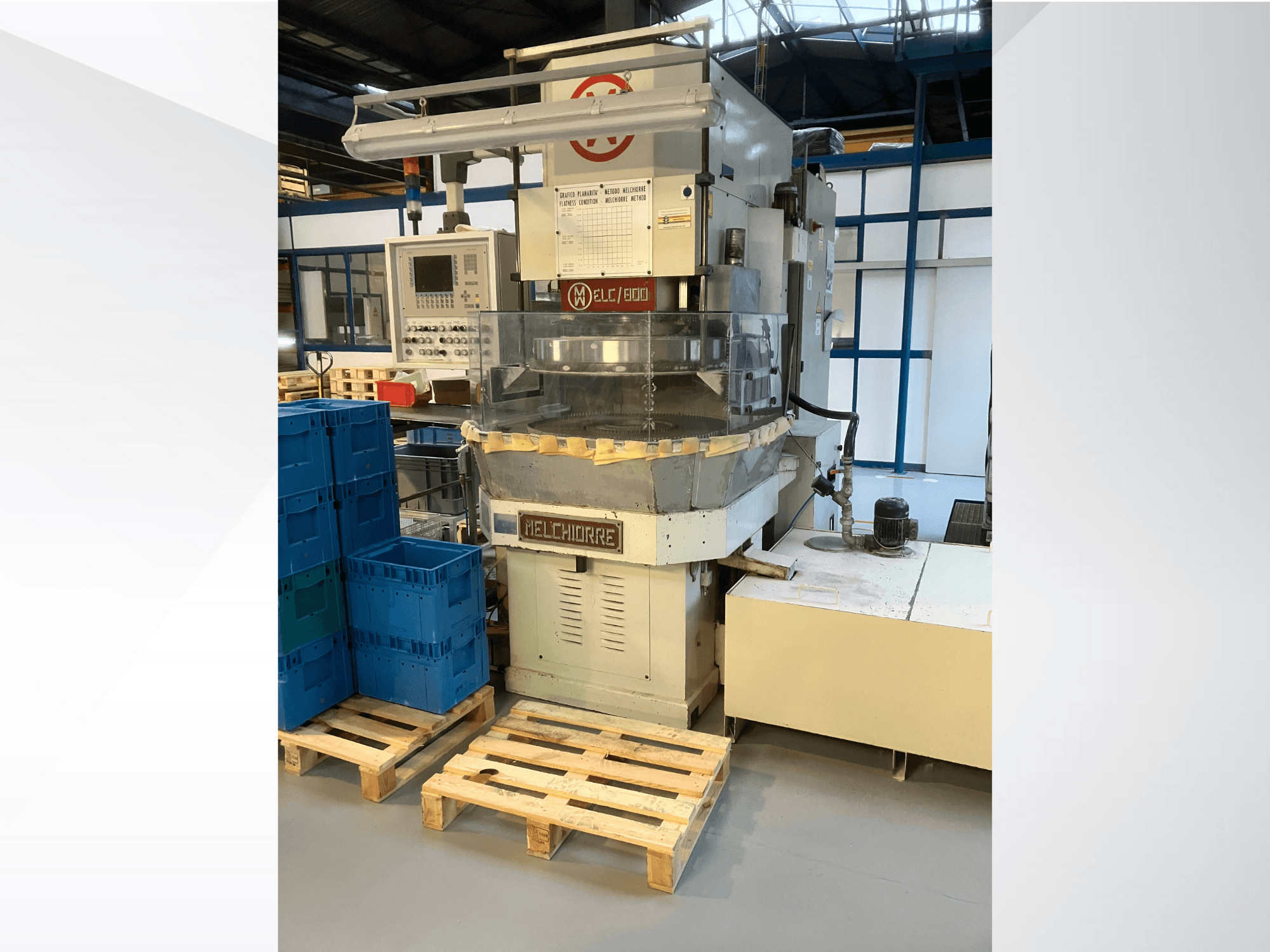 Industriële machine van Melchiorre in vooraanzicht, met bedieningspaneel, transparante trechter en blauwe kratten op houten pallets.