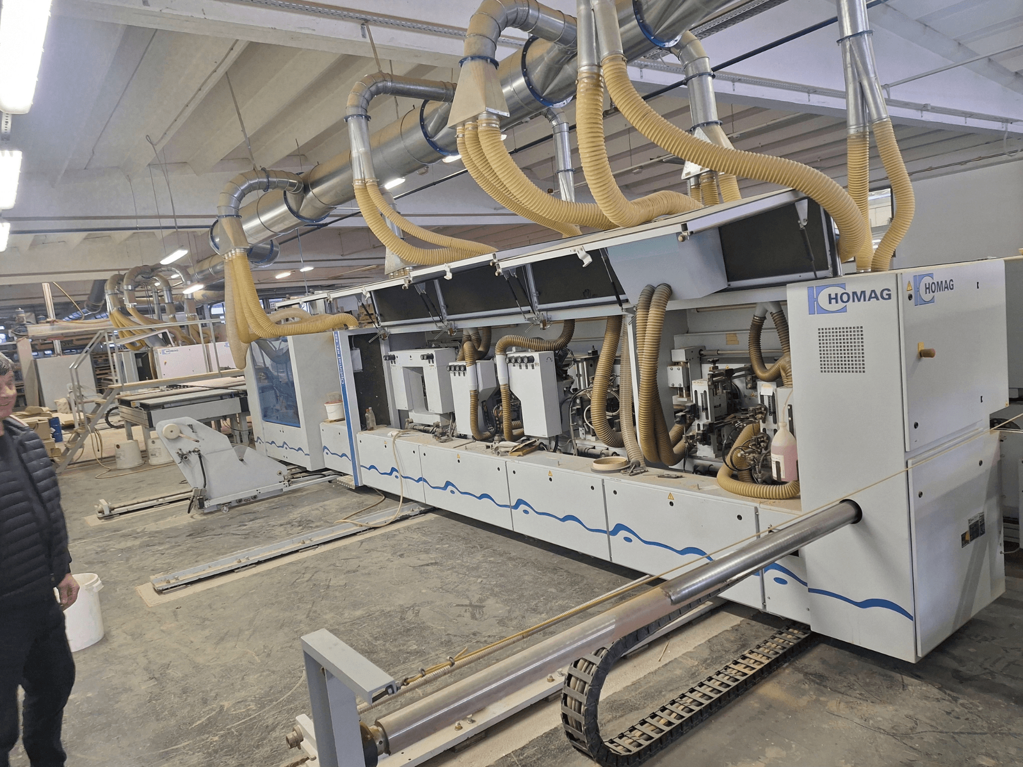 HOMAG houtbewerkingsmachine in een fabrieksomgeving, vooraanzicht met meerdere spindels en stofafzuigsysteem.