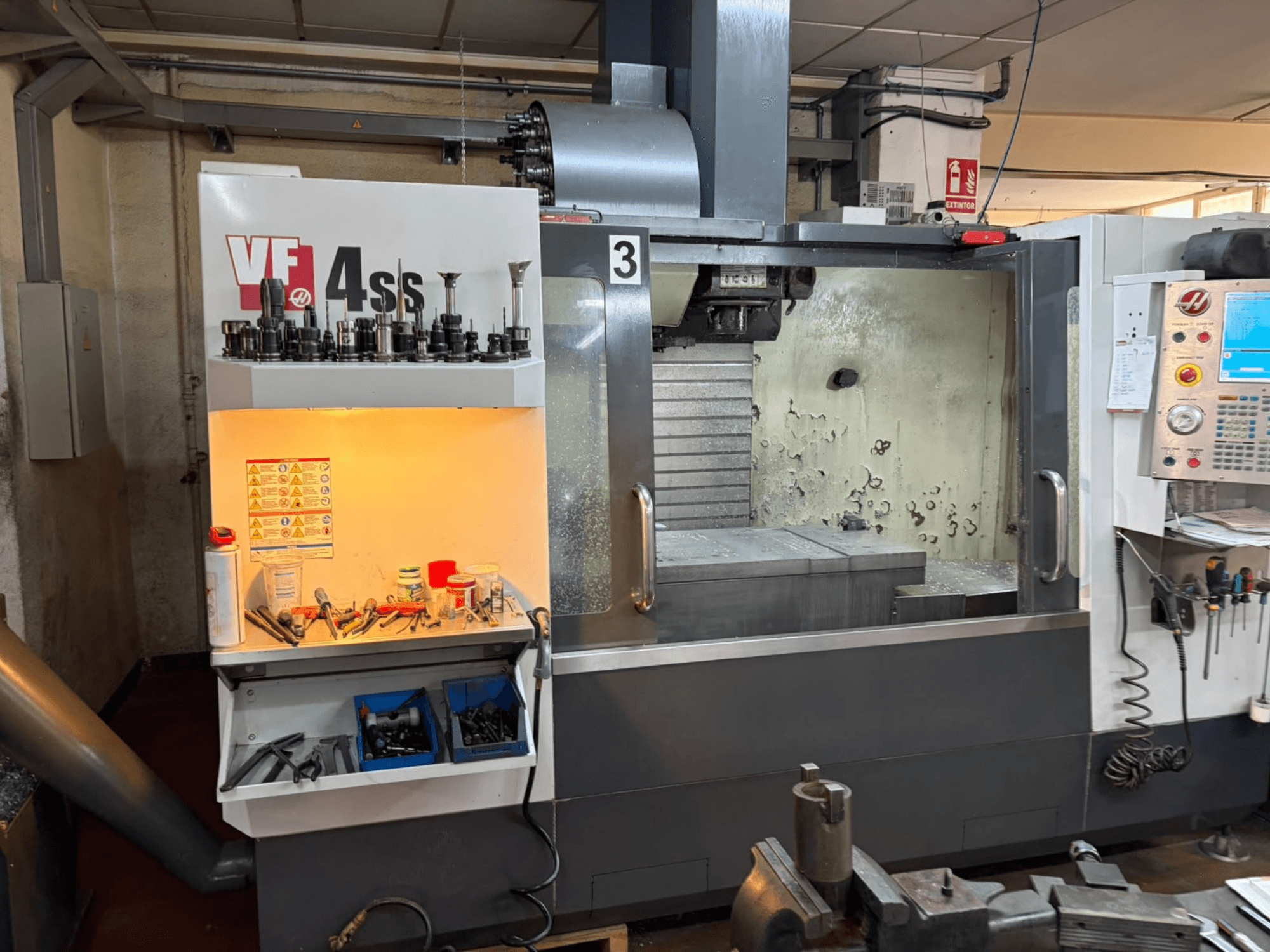 HAAS VP 4SS verticaal bewerkingscentrum, vooraanzicht, met gereedschapopslag, bedieningspaneel en zichtbaar werkgebied met bewerkingsdetails.