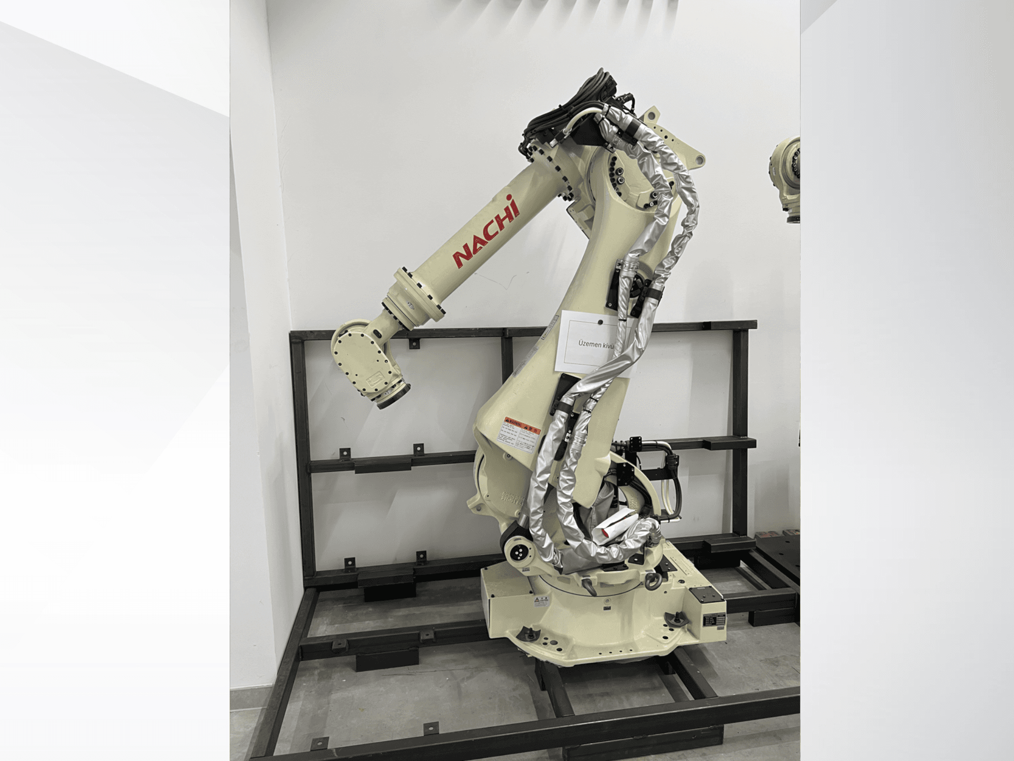 NACHI SRA166-01 robotarm in zijaanzicht, met flexibele gewrichten, bevestigde kabels en gemonteerd op een beschermend frame.