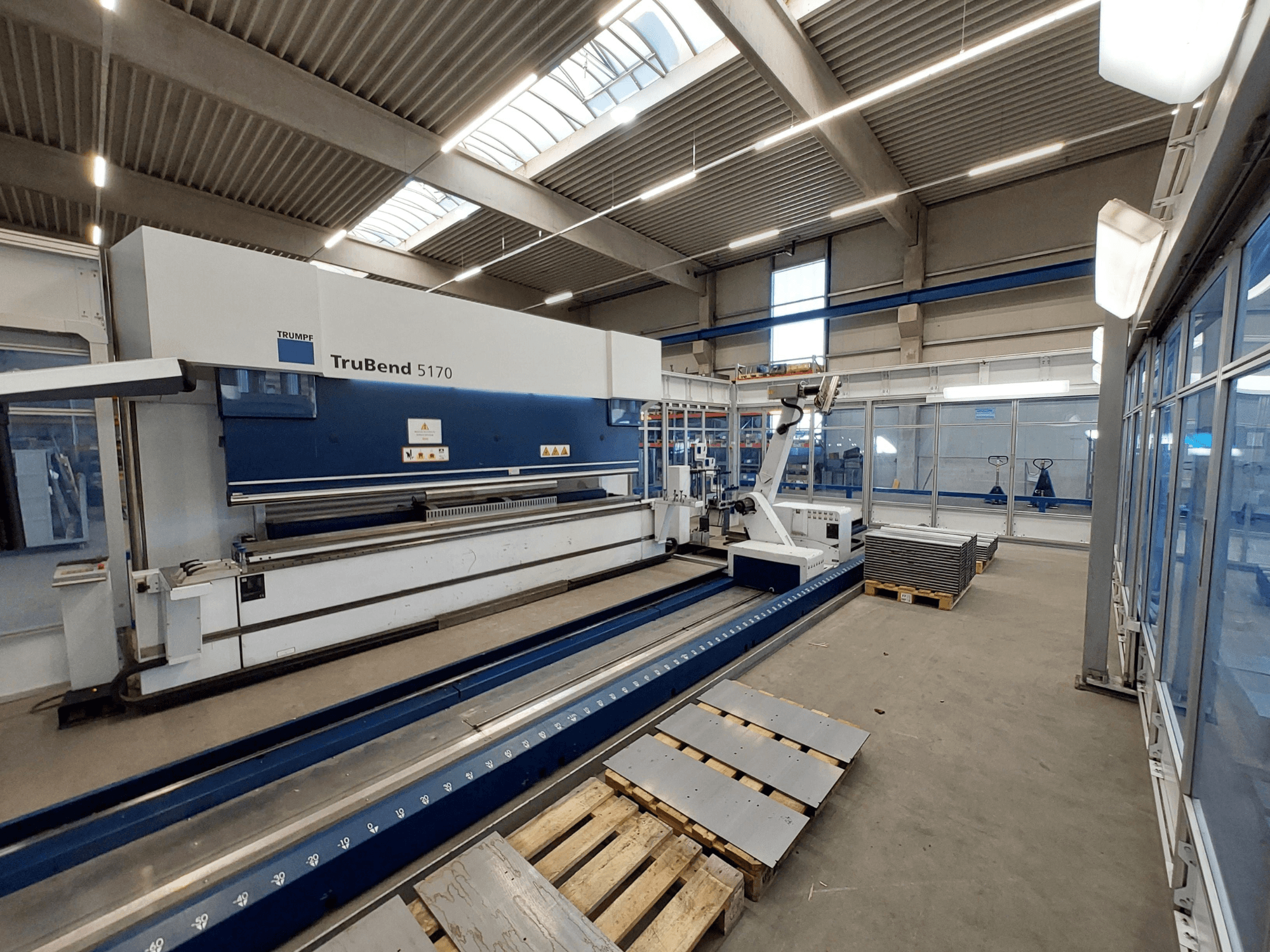 TRUMPF TruBend 5170 afkantpers in een werkplaats, zijaanzicht, met buiggereedschap en gestapelde metalen platen op pallets.