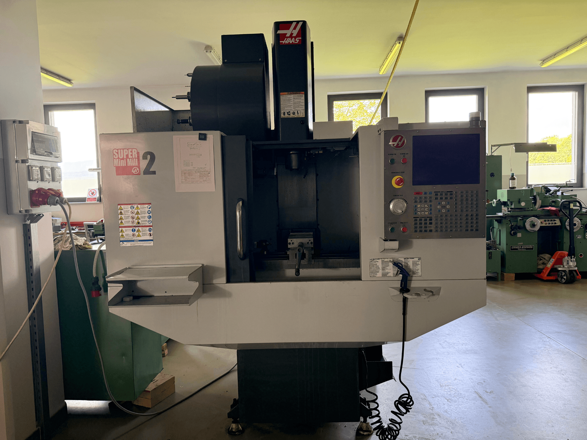 Haas Mini Mill 2 verticaal bewerkingscentrum in vooraanzicht, met het bedieningspaneel en het gereedschapgebied met waarschuwingslabels.