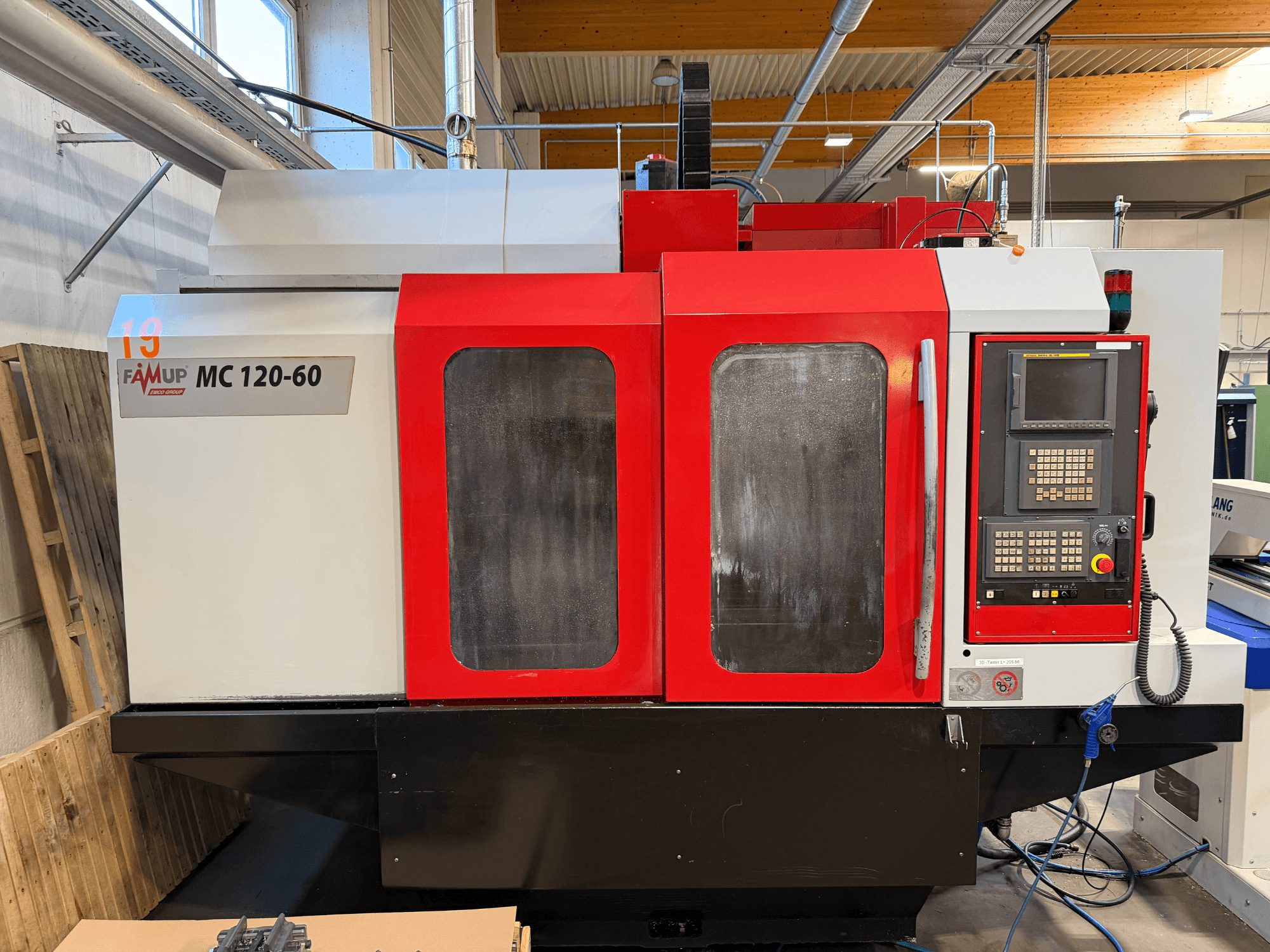 Vooraanzicht van EMCO MC 120-60 verticaal bewerkingscentrum met rood-witte behuizing, bedieningspaneel en display.