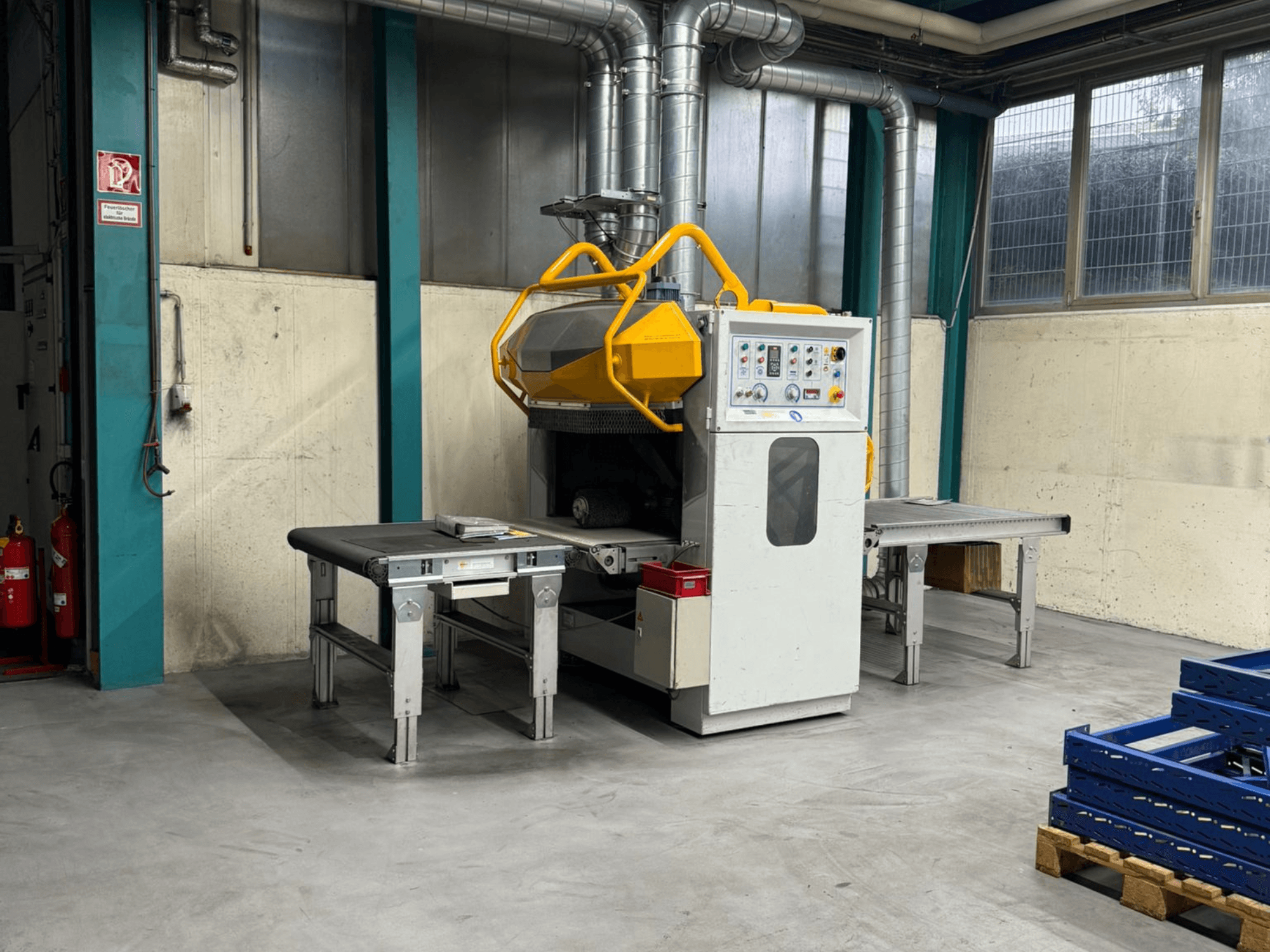 Ontbramingsmachine Fladder AUT-1000 VAC in een fabrieksomgeving, met bedieningspaneel, geel veiligheidsscherm en aangrenzende werktafels.