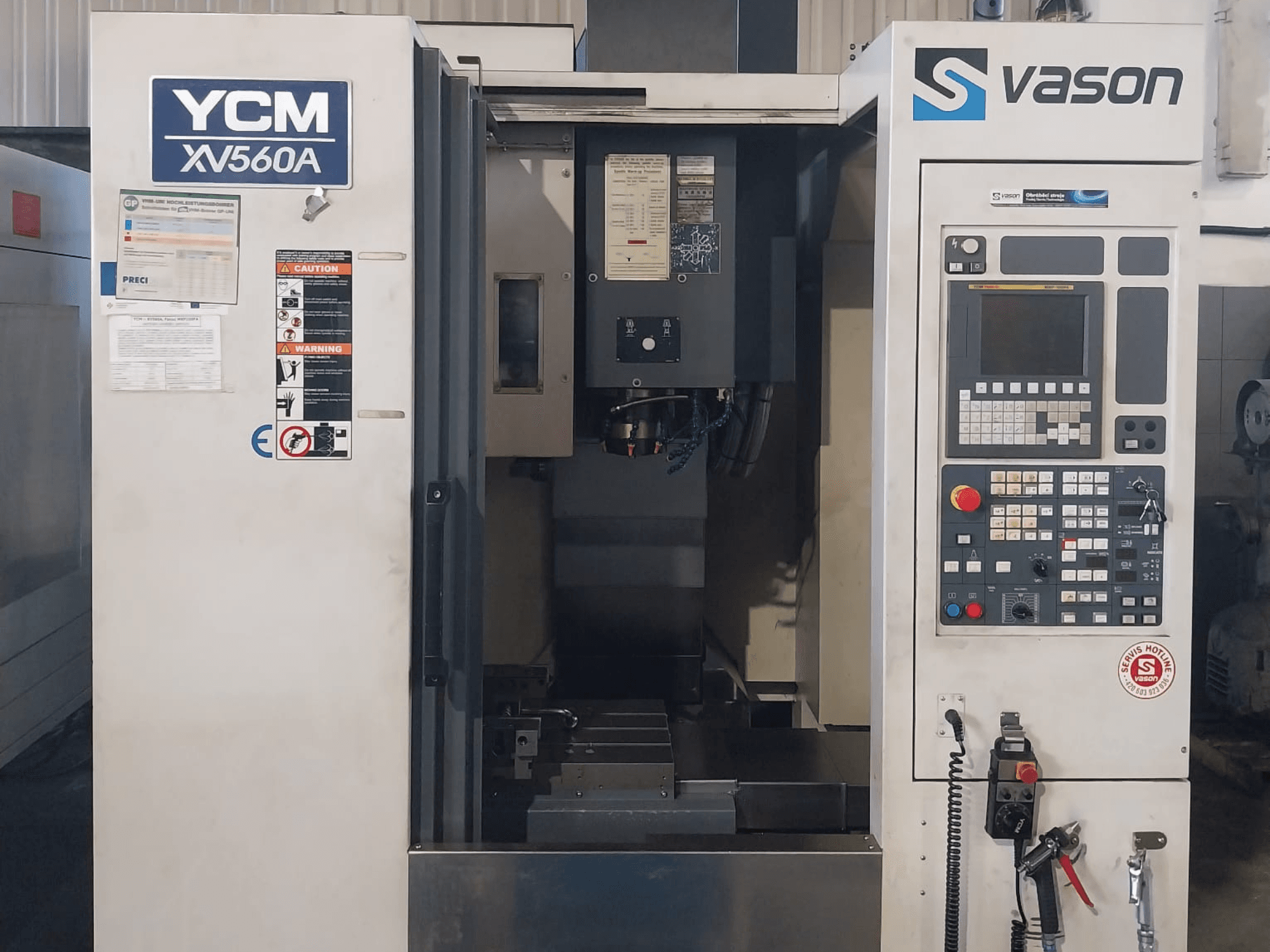 Vooraanzicht van YCM XV 560A verticaal bewerkingscentrum, met bedieningspaneel en werktafel met zichtbare bewerkingscomponenten.