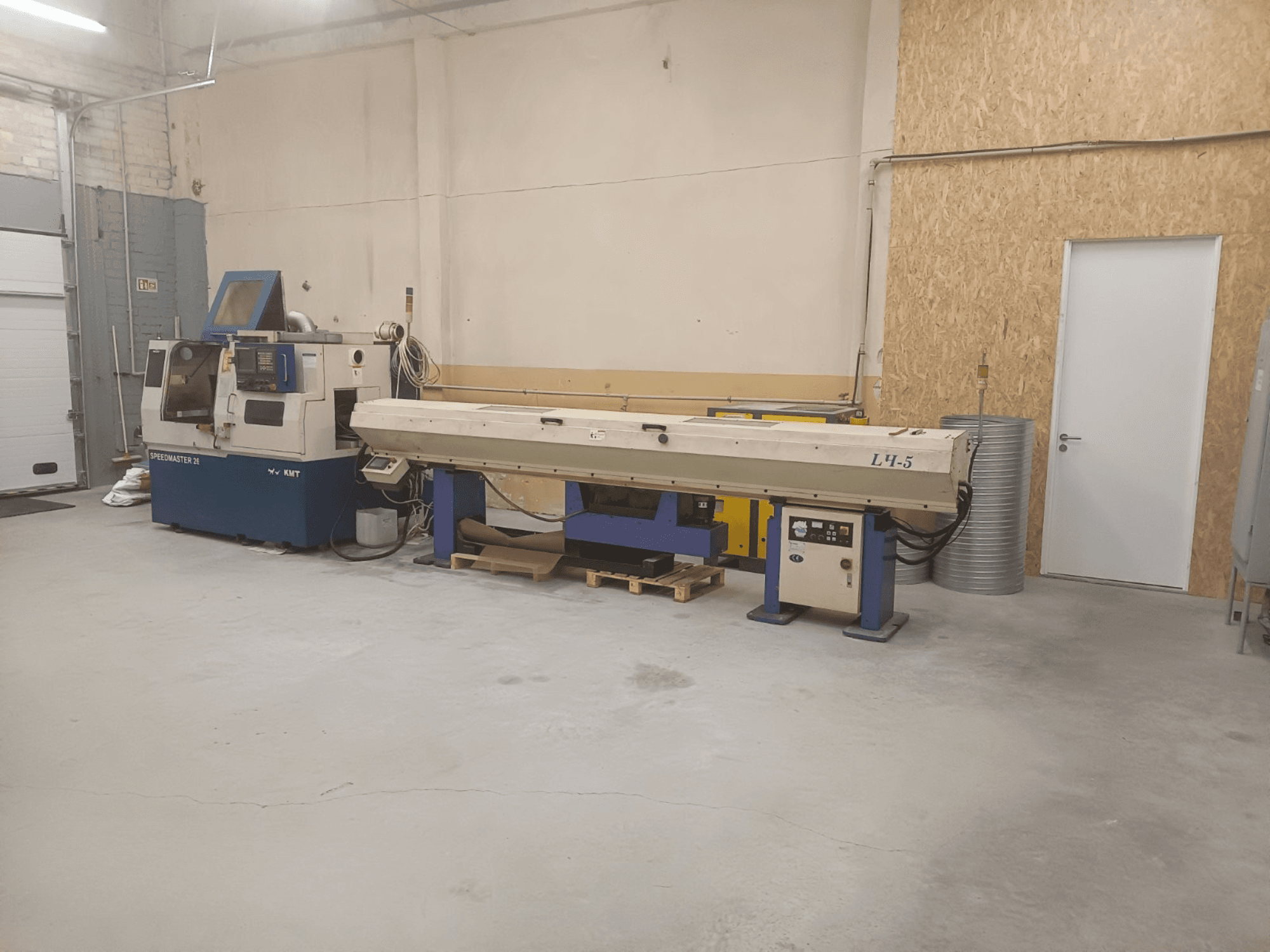 Industriële werkplaats met KMT Speedmaster 34 machine en L4.5, gezien vanaf de voorkant, met zichtbare bedieningselementen en machines.