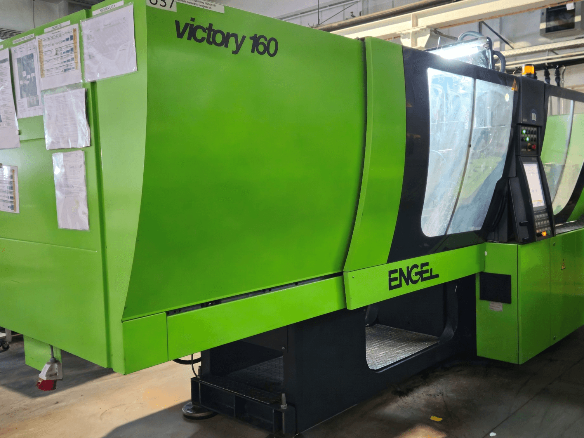 Groene ENGEL Victory 160 spuitgietmachine, zijaanzicht, met bedieningspaneel, veiligheidsverlichting en werkpapieren.