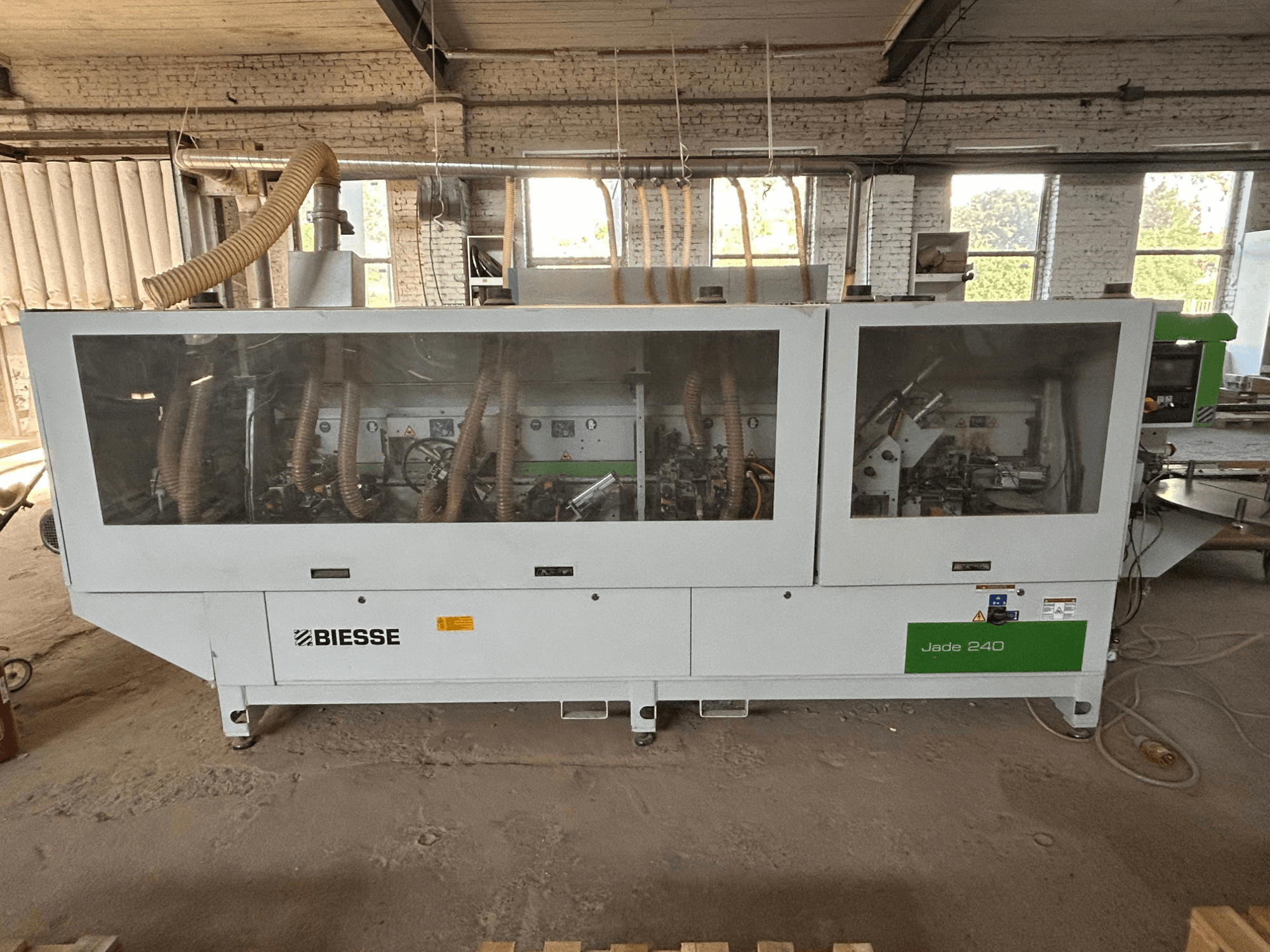 BIESSE Jade 240 kantenlijmmachine in wit en groen, vooraanzicht met bedieningspaneel en gedetailleerd zicht op de binnenkant van de machine.