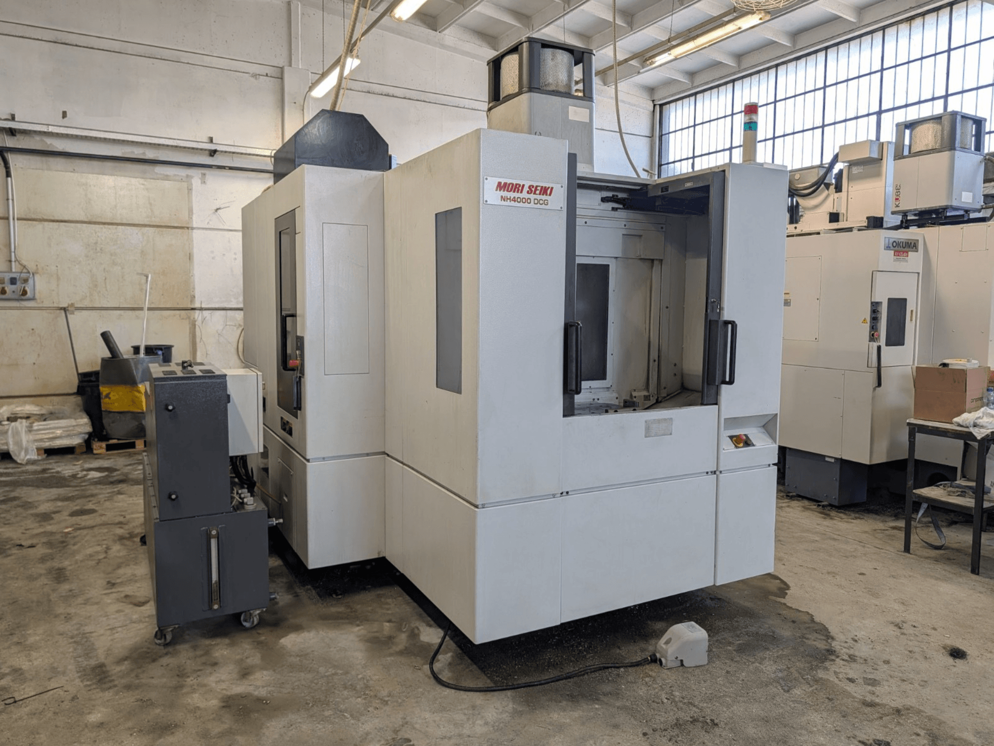 MORI SEIKI NH 4000 DCG horizontaal bewerkingscentrum, vooraanzicht, weergave van bedieningspaneel en werkgebied, afwerking grijs en wit.