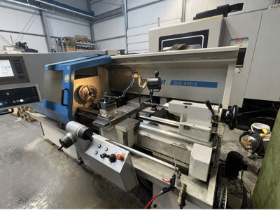 CNC draaibank DUS 400 ti vanuit vooraanzicht, met bedieningspaneel, gereedschaphouder en verlichte werkruimte.