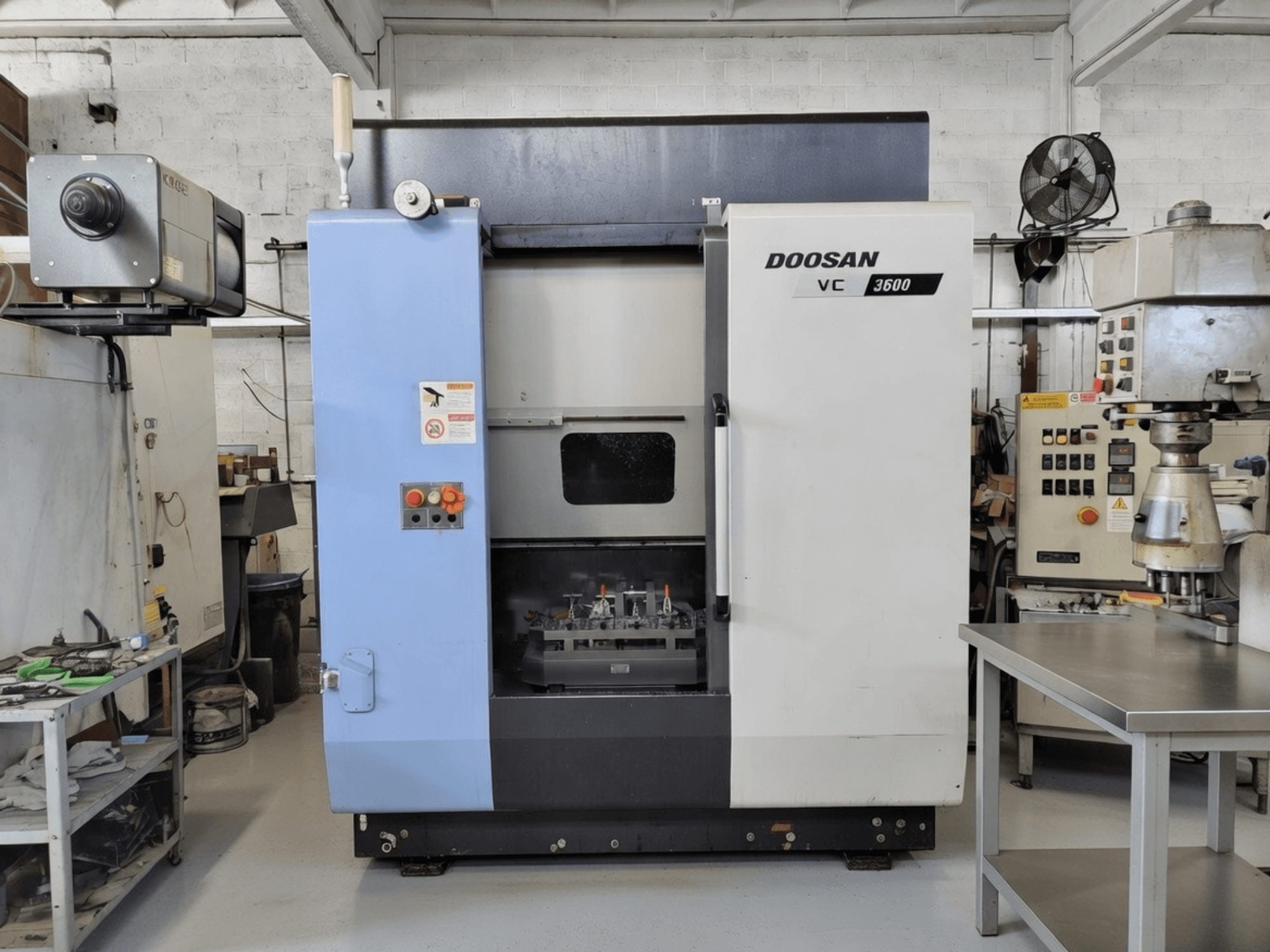 DOOSAN VC 3600 verticaal bewerkingscentrum in vooraanzicht, met bedieningspaneel en open deur die de werkruimte onthult.