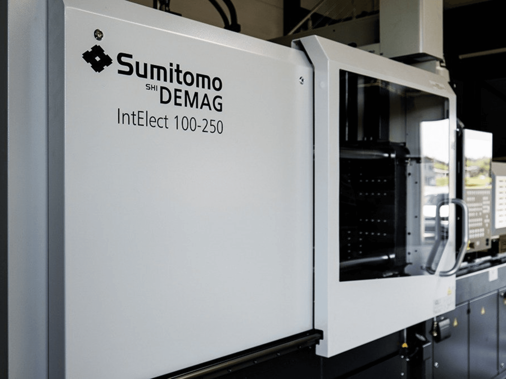 Vooraanzicht van de SUMITOMO SHI DEMAG IntElect 100/250 elektrische spuitgietmachine met bedieningspaneel en veiligheidsvoorzieningen.
