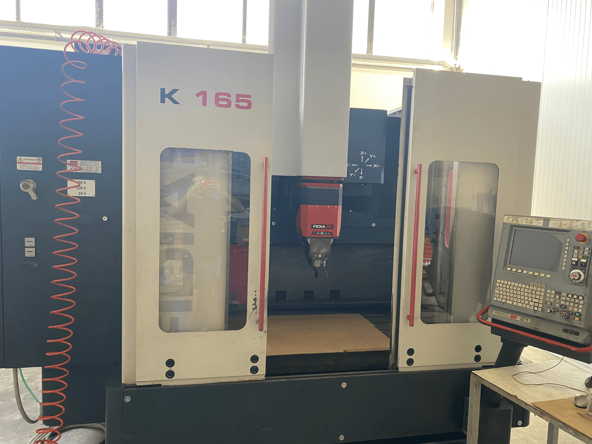 Fidia K 165 CNC machine met een rode spindel en bedieningspaneel, gezien vanaf de voorkant, in een goed verlichte werkplaats.