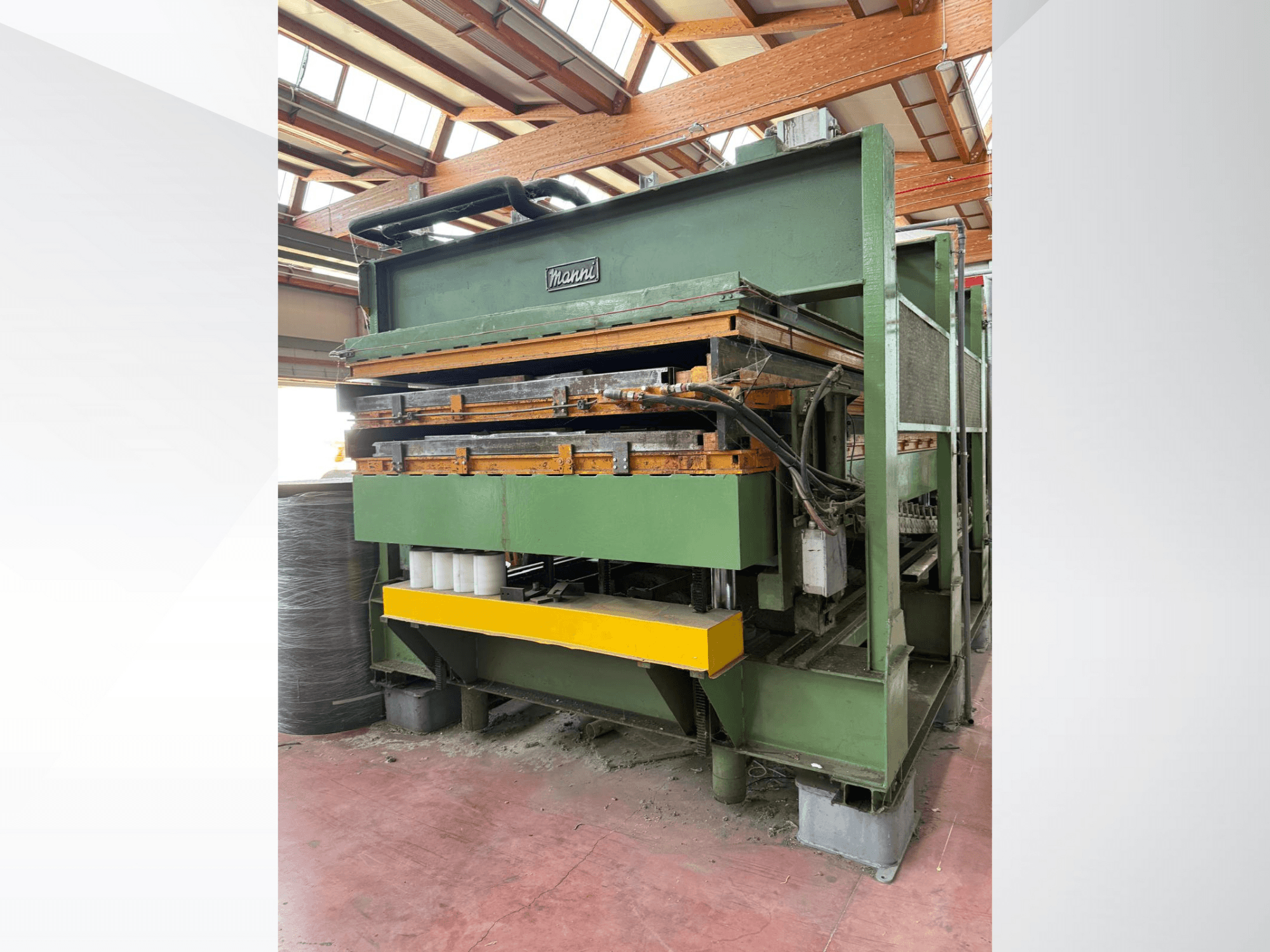 Hydraulische pers van Manni, zijaanzicht, met groen metalen huis, gele basis en meerdere hydraulische leidingen zichtbaar.