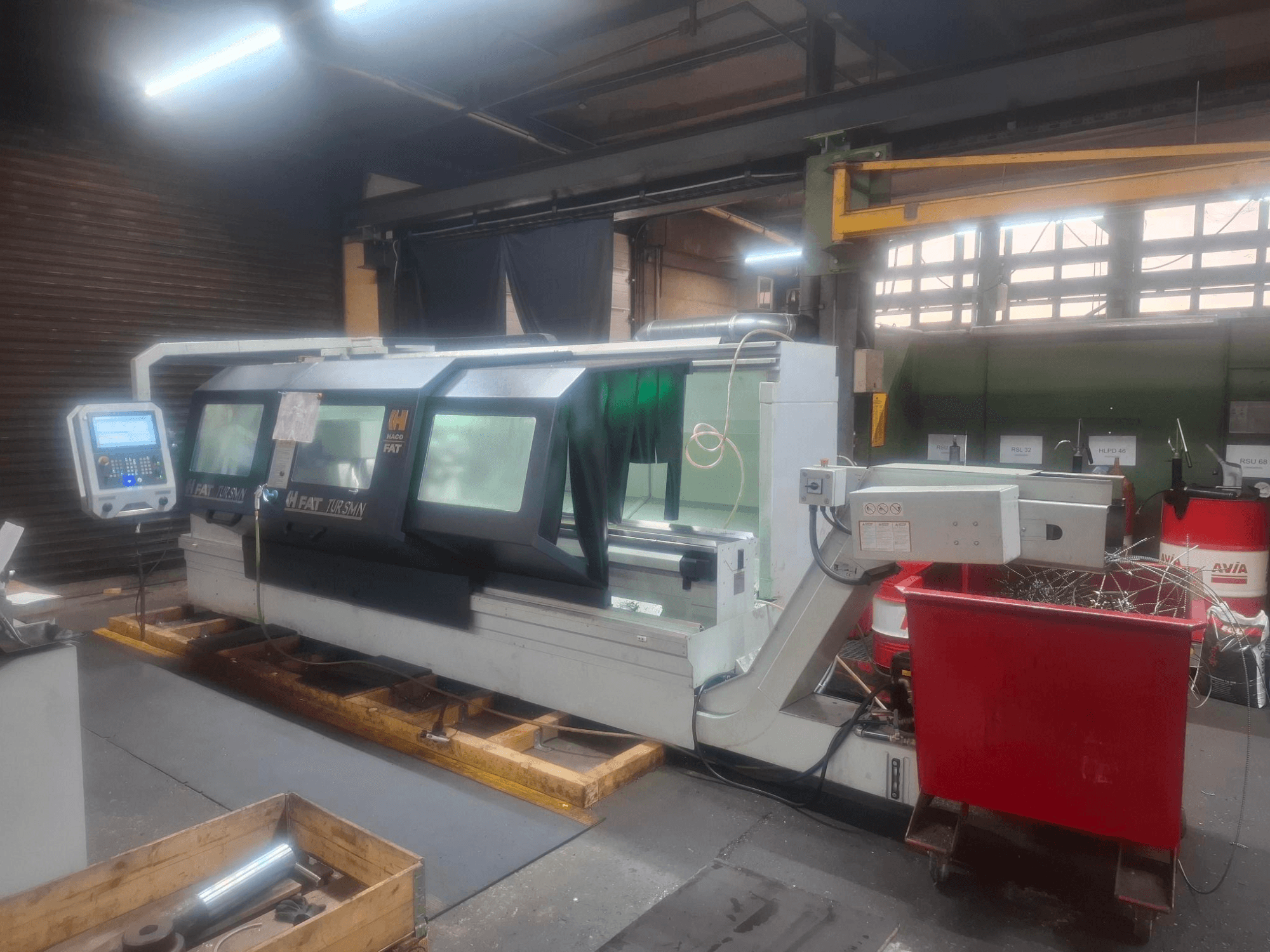 Vooraanzicht van een FAT Tursan CNC machine met bedieningspaneel, geplaatst op houten pallets in een werkplaats.