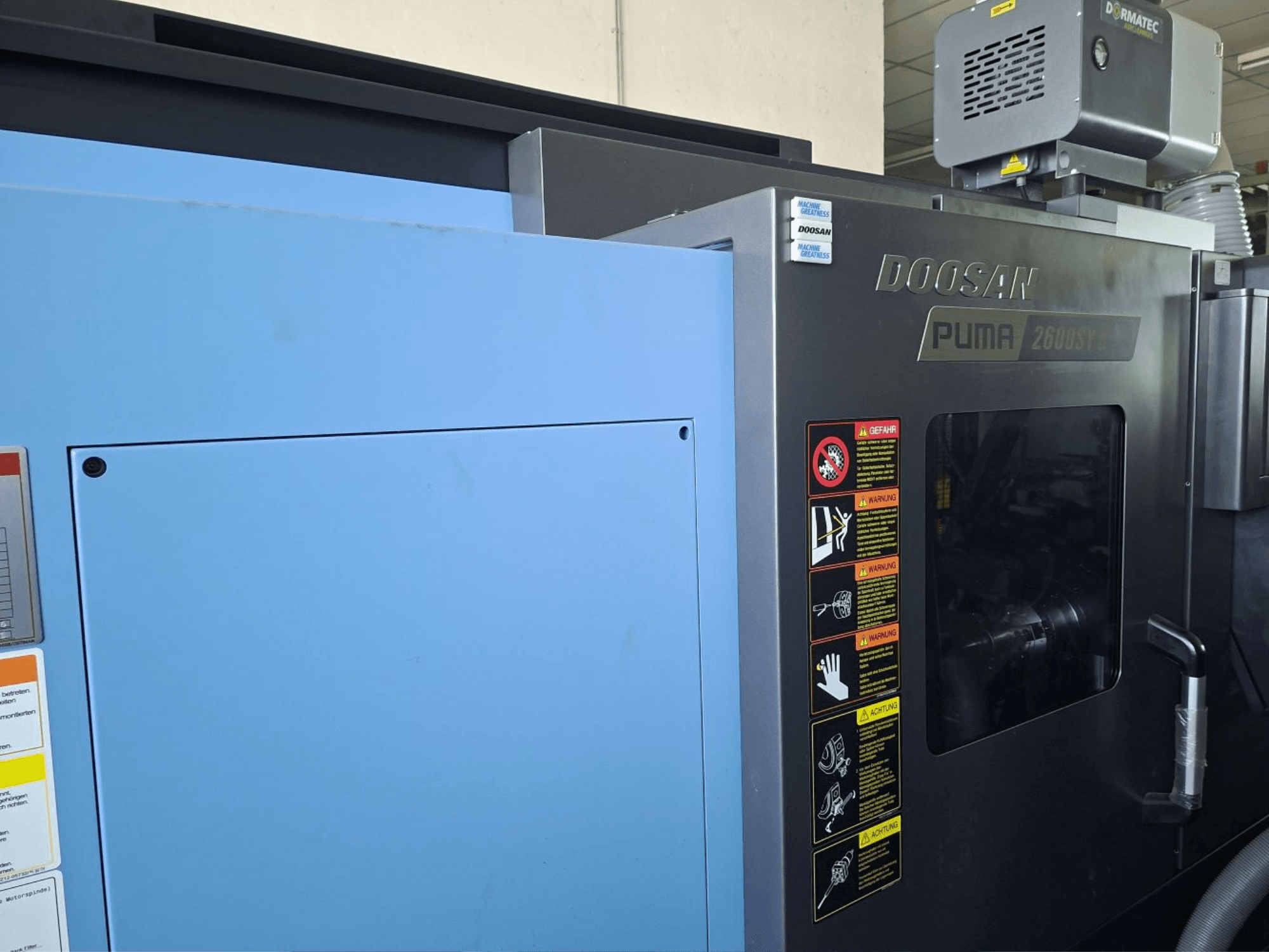 DOOSAN PUMA 2600 SY II horizontale draaimachine, vooraanzicht, met veiligheidslabels en blauwe bekleding.