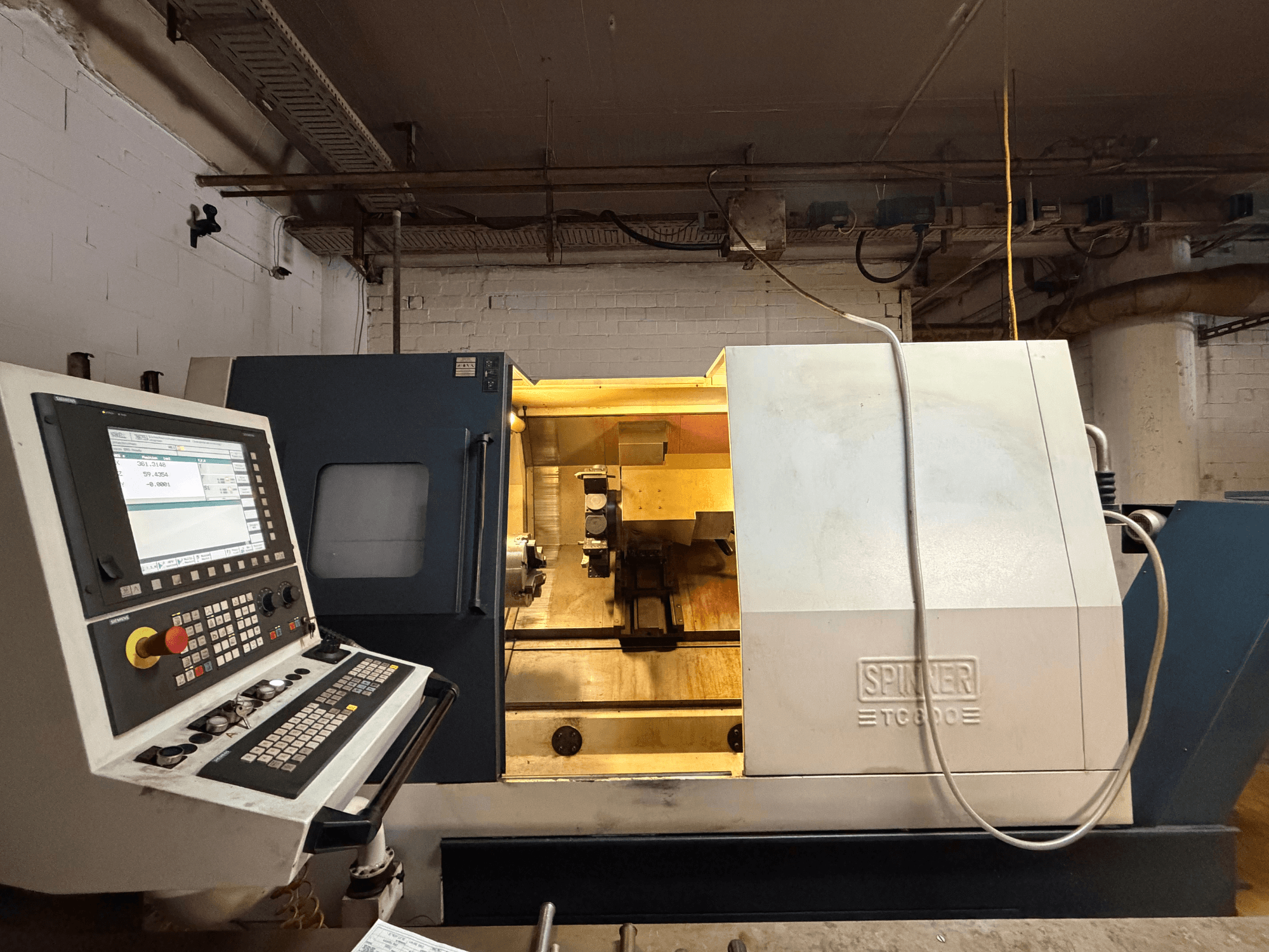SPINNER TC800 horizontale draaimachine in een werkplaats, met een bedieningspaneel en zichtbare interne componenten.