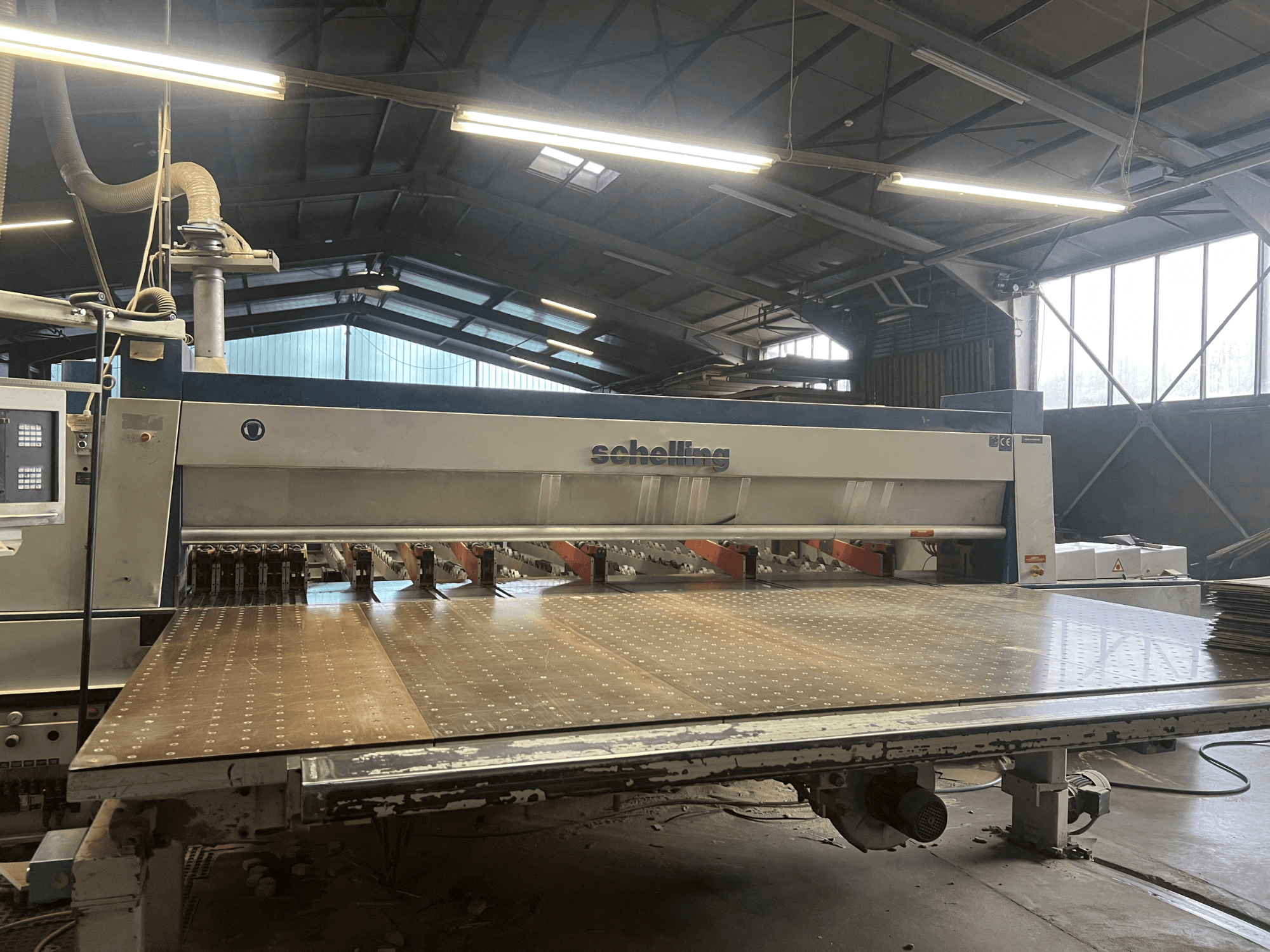 Schelling paneelzaag met vooraanzicht, met een grote geperforeerde zaagtafel en meerdere bladen voor nauwkeurig zagen van hout.
