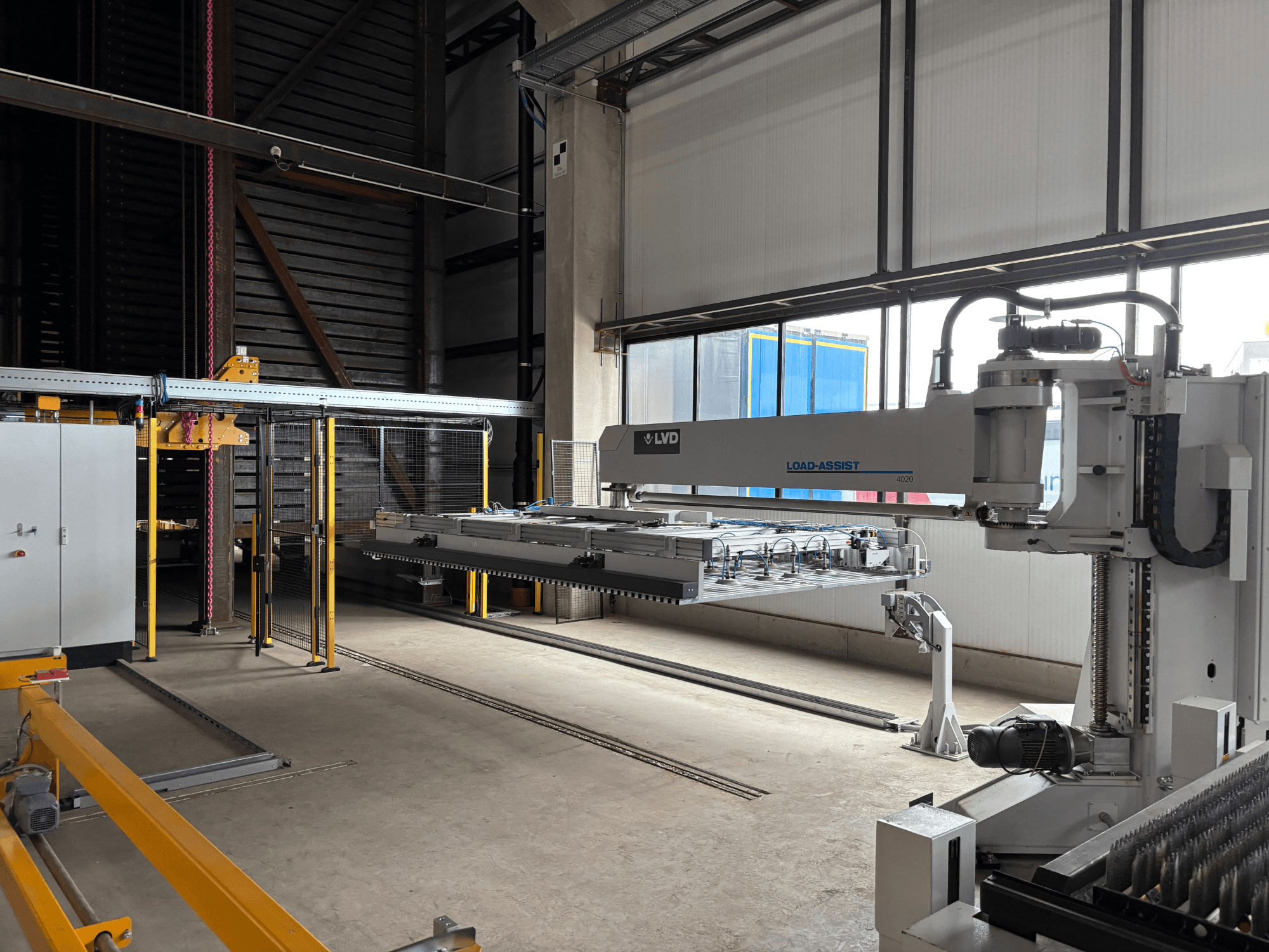 LVD Load-Assist 4020 automatiseringsapparatuur in vooraanzicht met een robotarm en laadsysteem zichtbaar in een grote werkruimte.