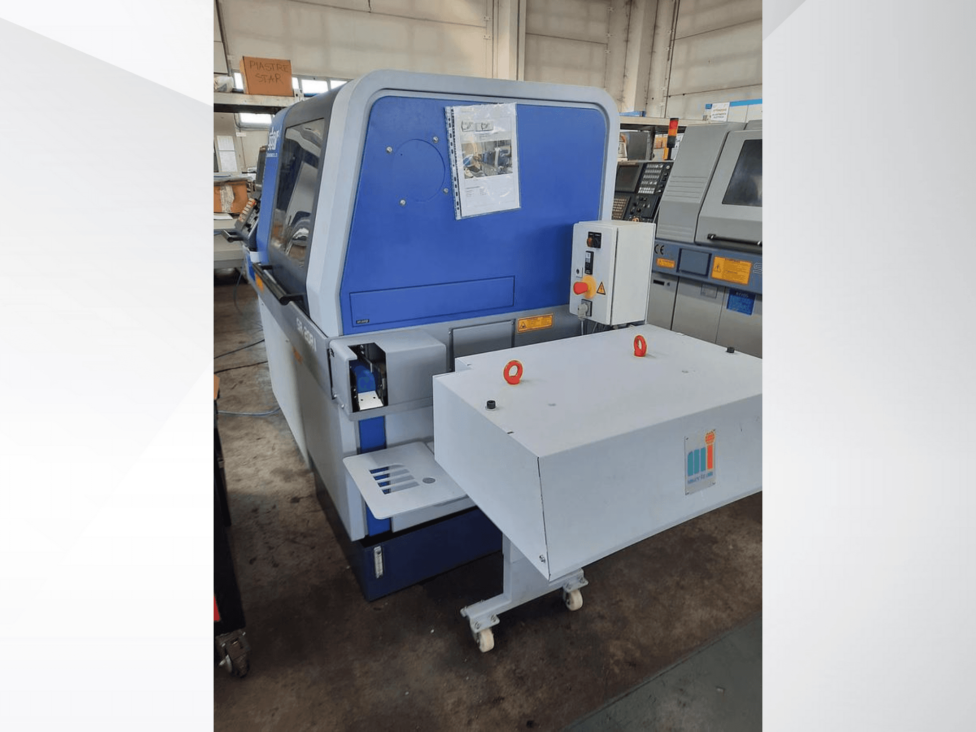 Blauwe industriële machine met een witte transportband, met het bedieningspaneel en bijgevoegde veiligheidsvoorzieningen, zijaanzicht.