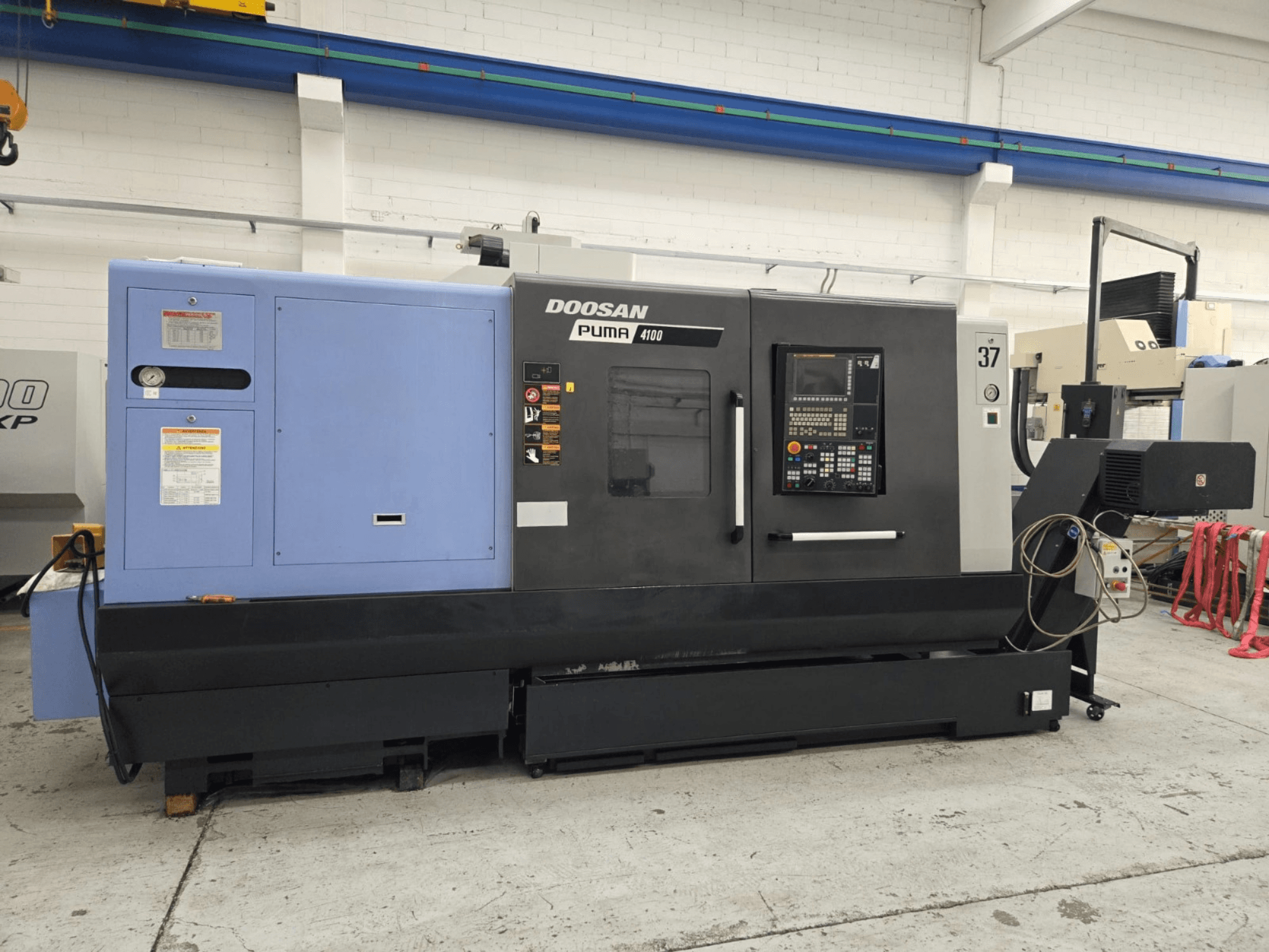 Doosan Puma 4100 CNC draaibank, vooraanzicht; voorzien van bedieningspaneel, blauwe voedingseenheid en gedetailleerde labels voor operationele begeleiding.