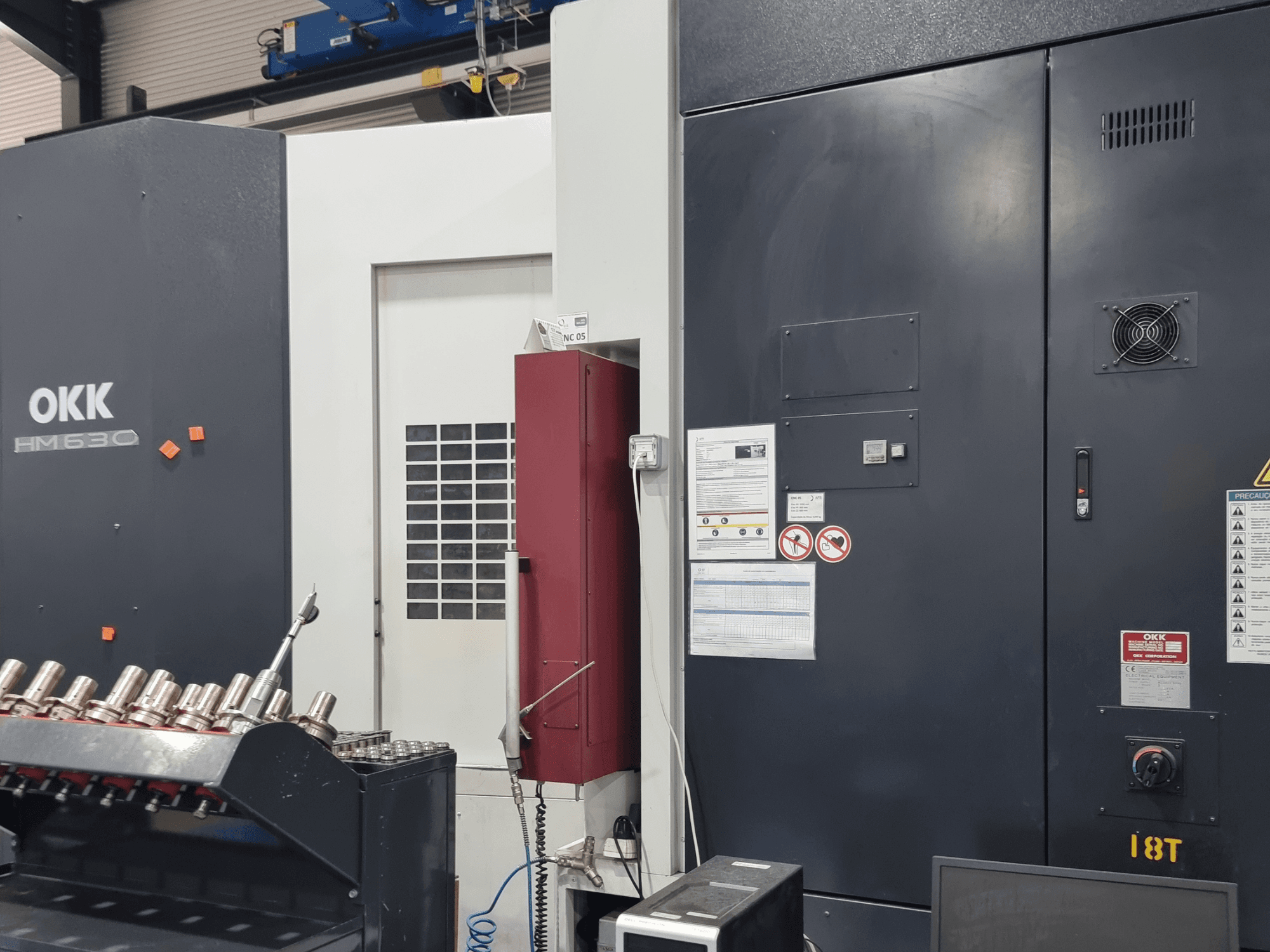 OKK HM630 horizontaal bewerkingscentrum, vooraanzicht met bedieningspaneel, veiligheidsaanwijzingen en gereedschapopslag aan de zijkant.