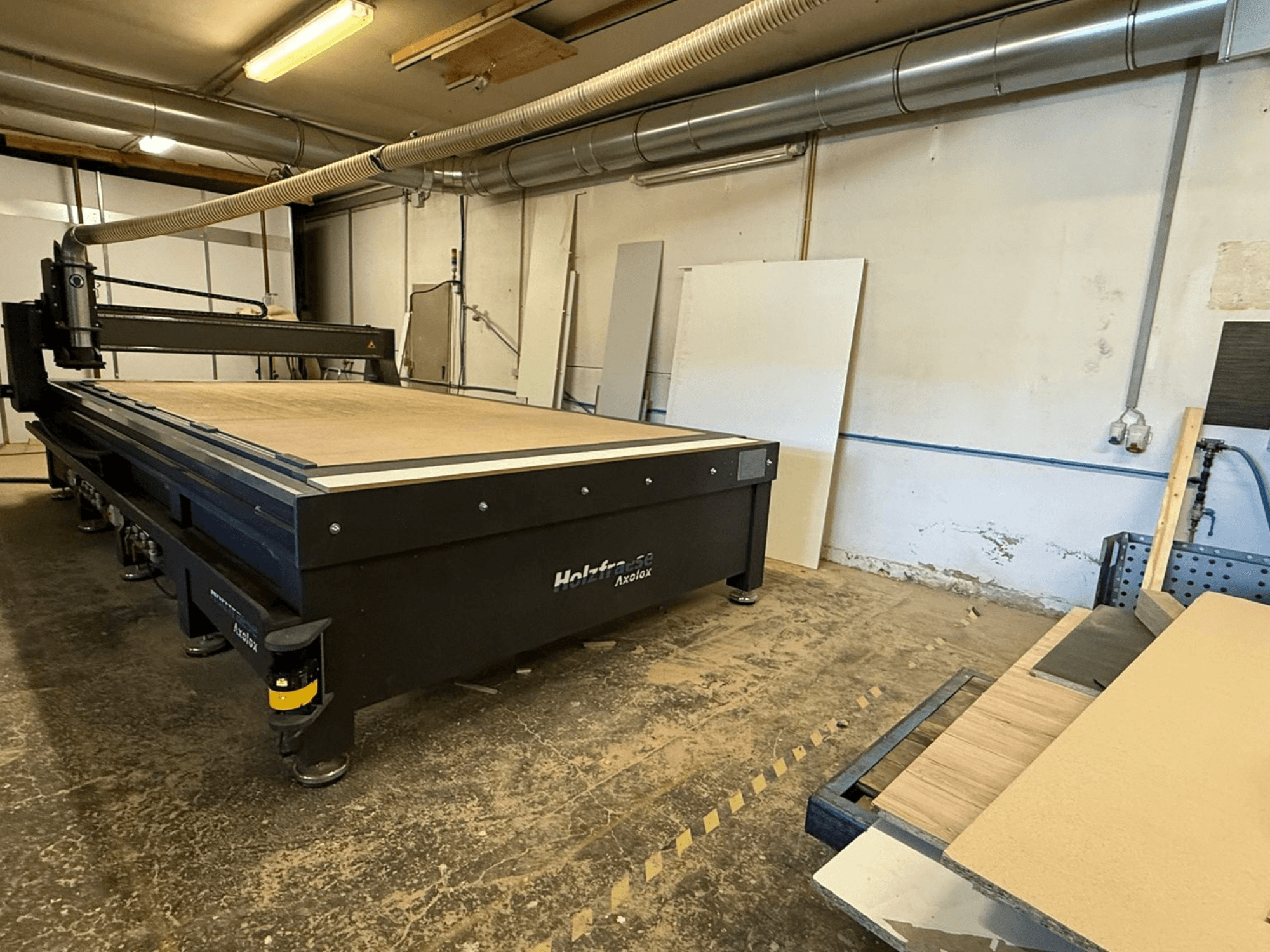 Holz-Her Axos 5 CNC frees in werkplaats, vooraanzicht met werktafel, stofafzuigsysteem en houten panelen in de buurt.