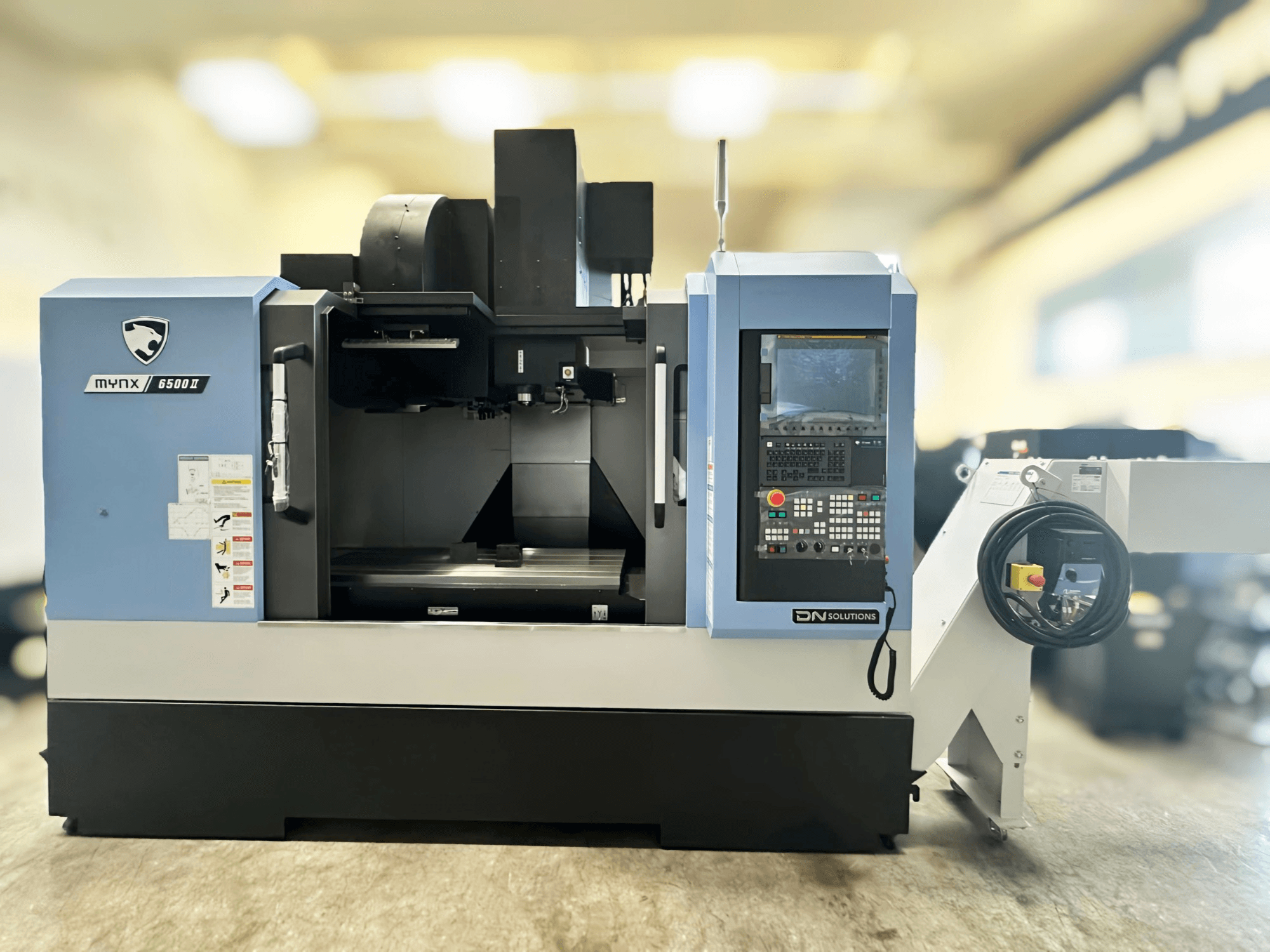 DN SOLUTIONS MYNX 6500 II verticaal bewerkingscentrum in vooraanzicht, met bedieningspaneel en bedieningsinterface.