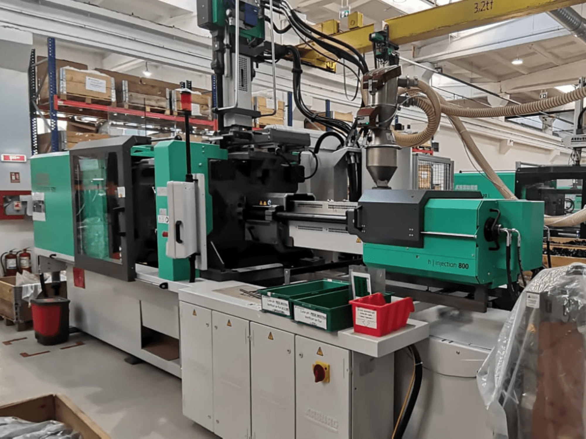 H injectie 800 machine in een fabriek, vooraanzicht, met een groen en zwart ontwerp, met bedieningspanelen en bakken voor onderdelen.