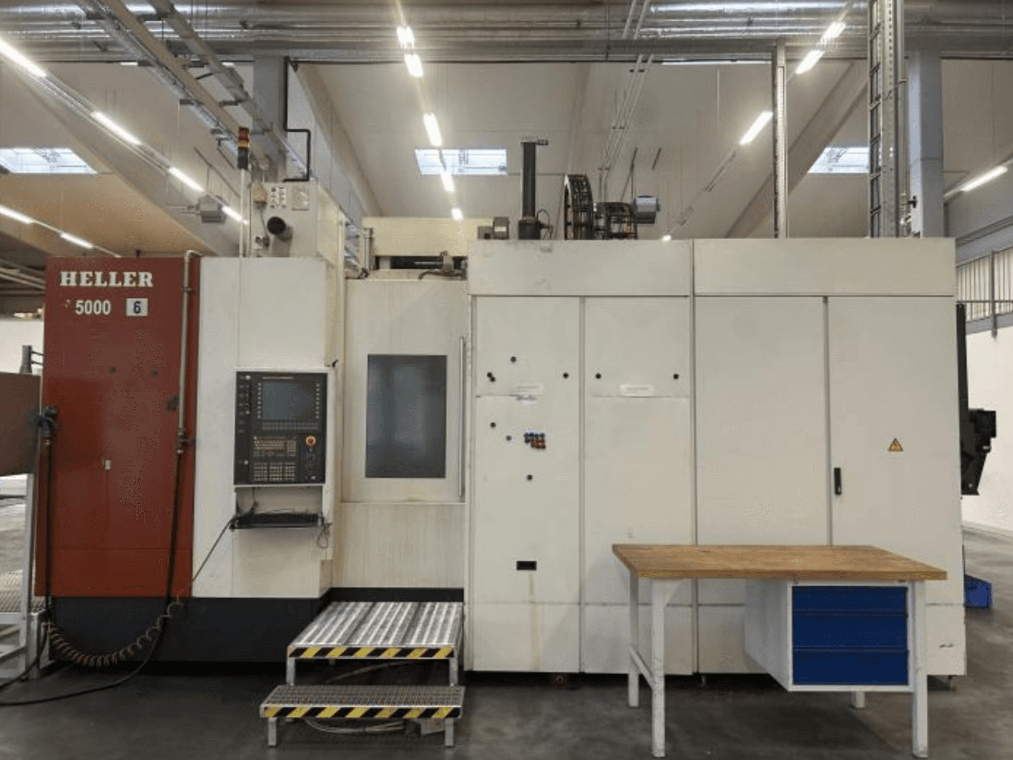 Vooraanzicht van het horizontale bewerkingscentrum HELLER H5000 met bedieningspaneel, opstapplatform en aangrenzende werktafel.