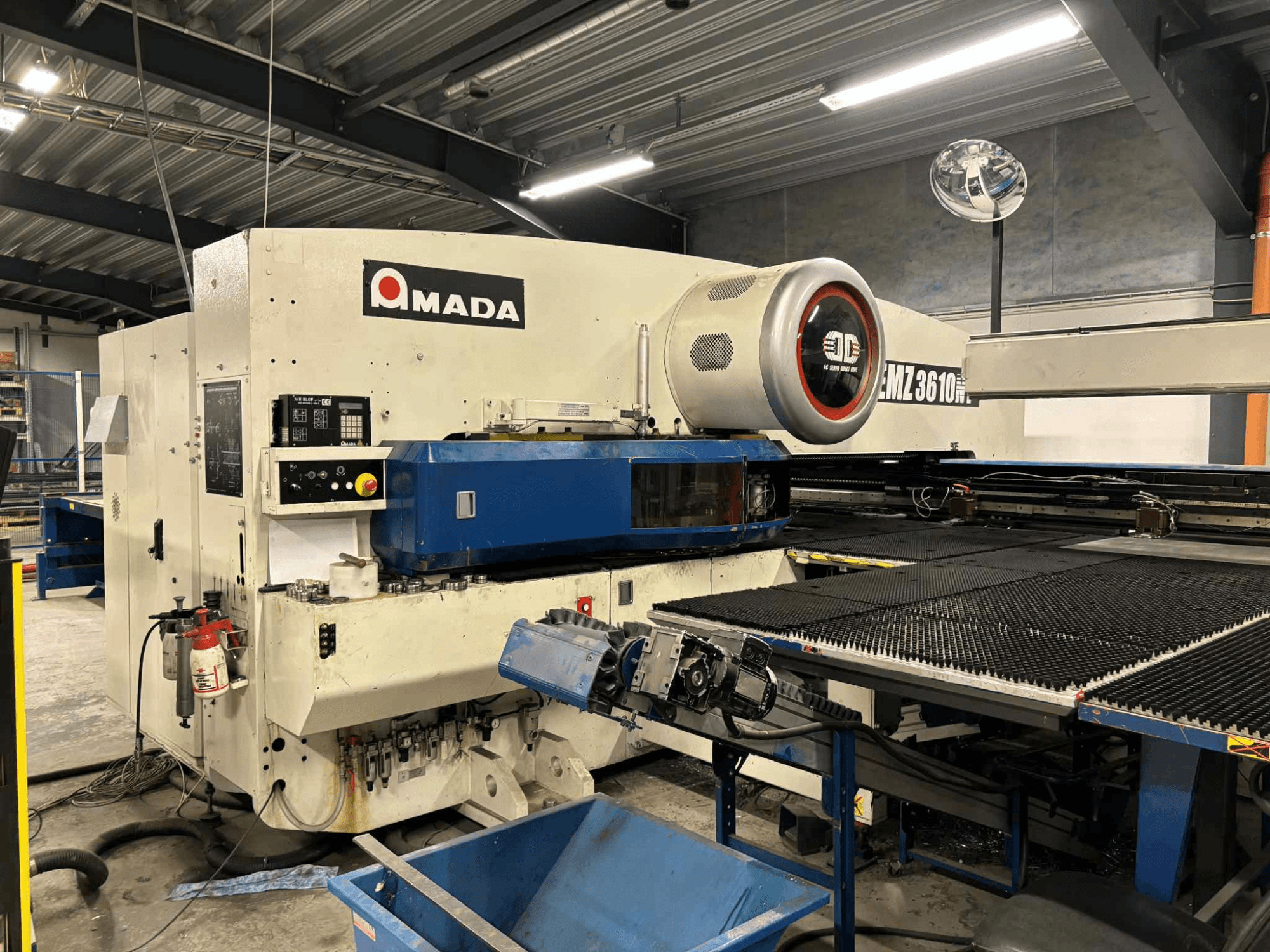 Amada EMZ3610H ponsmachine gezien vanaf de voorkant; voorzien van bedieningselementen, blauw bed en veiligheidsuitrusting.