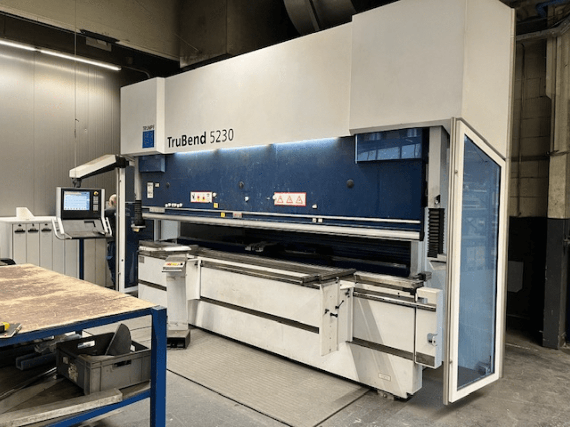 TruBend 5230 buigmachine in industriële omgeving; vooraanzicht met bedieningspaneel, veiligheidsfuncties en werktafel.