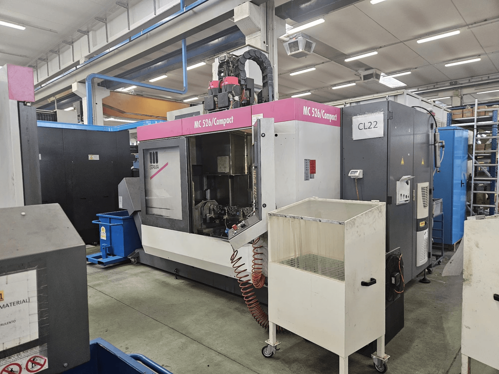 MC 526 Compact CNC machine van Stama, zijaanzicht, met bedieningspaneel, koelvloeistoftank en aangrenzende machines.