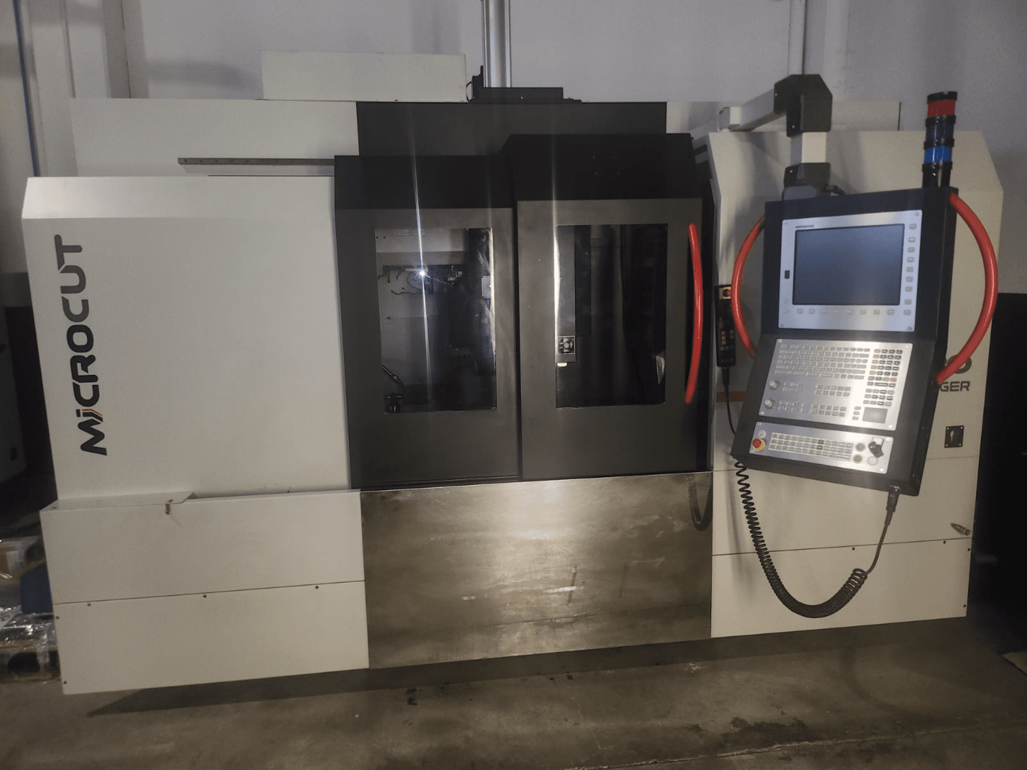 Microcut CNC machine gezien vanaf de voorkant; voorzien van bedieningspaneel, dubbele vensters, industrieel ontwerp en metalen afwerking.