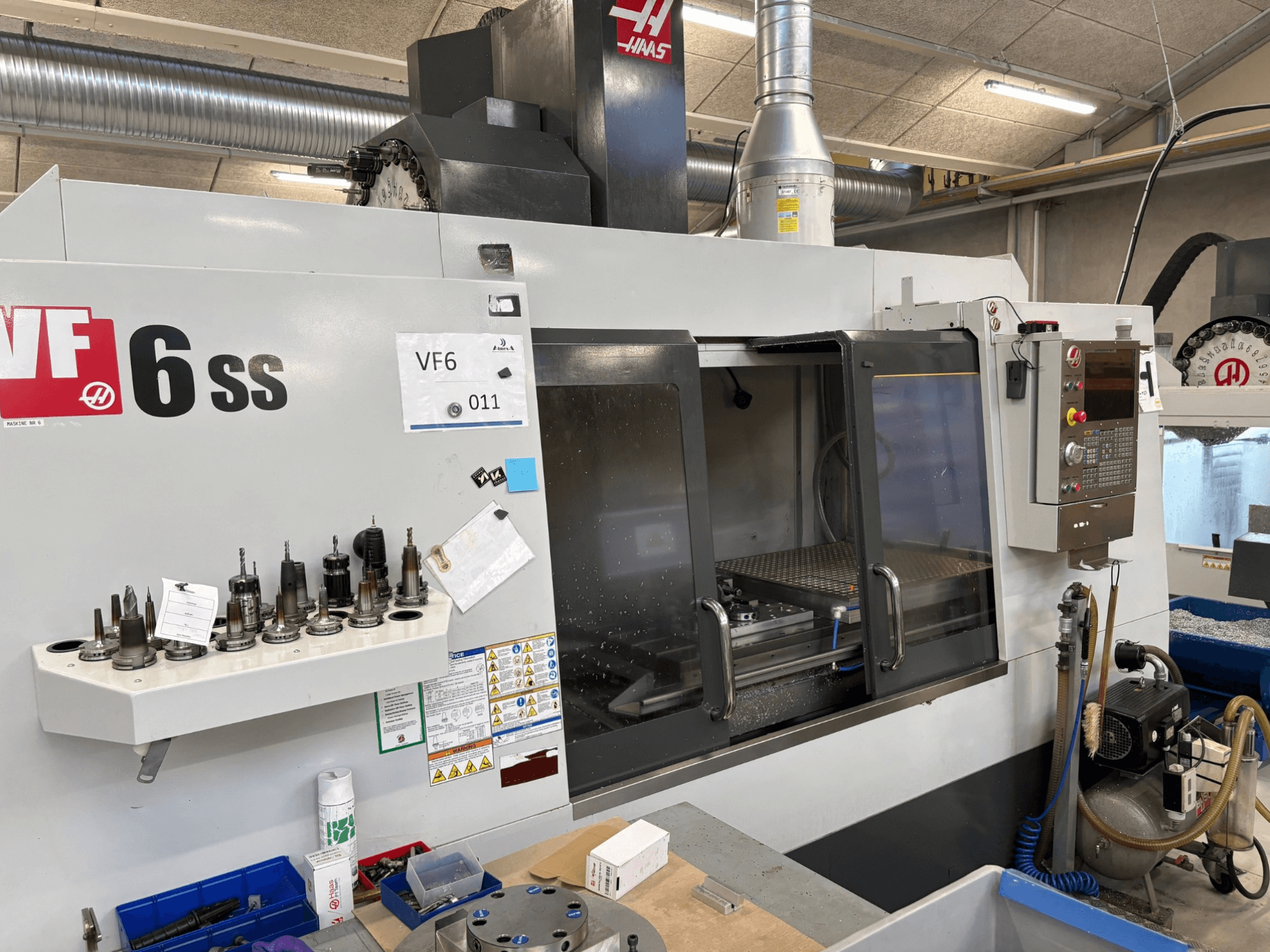 Haas VF-6 SS CNC freesmachine, vooraanzicht. Voorzien van diverse gereedschappen, bedieningspaneel en zichtbare interne werkruimte.