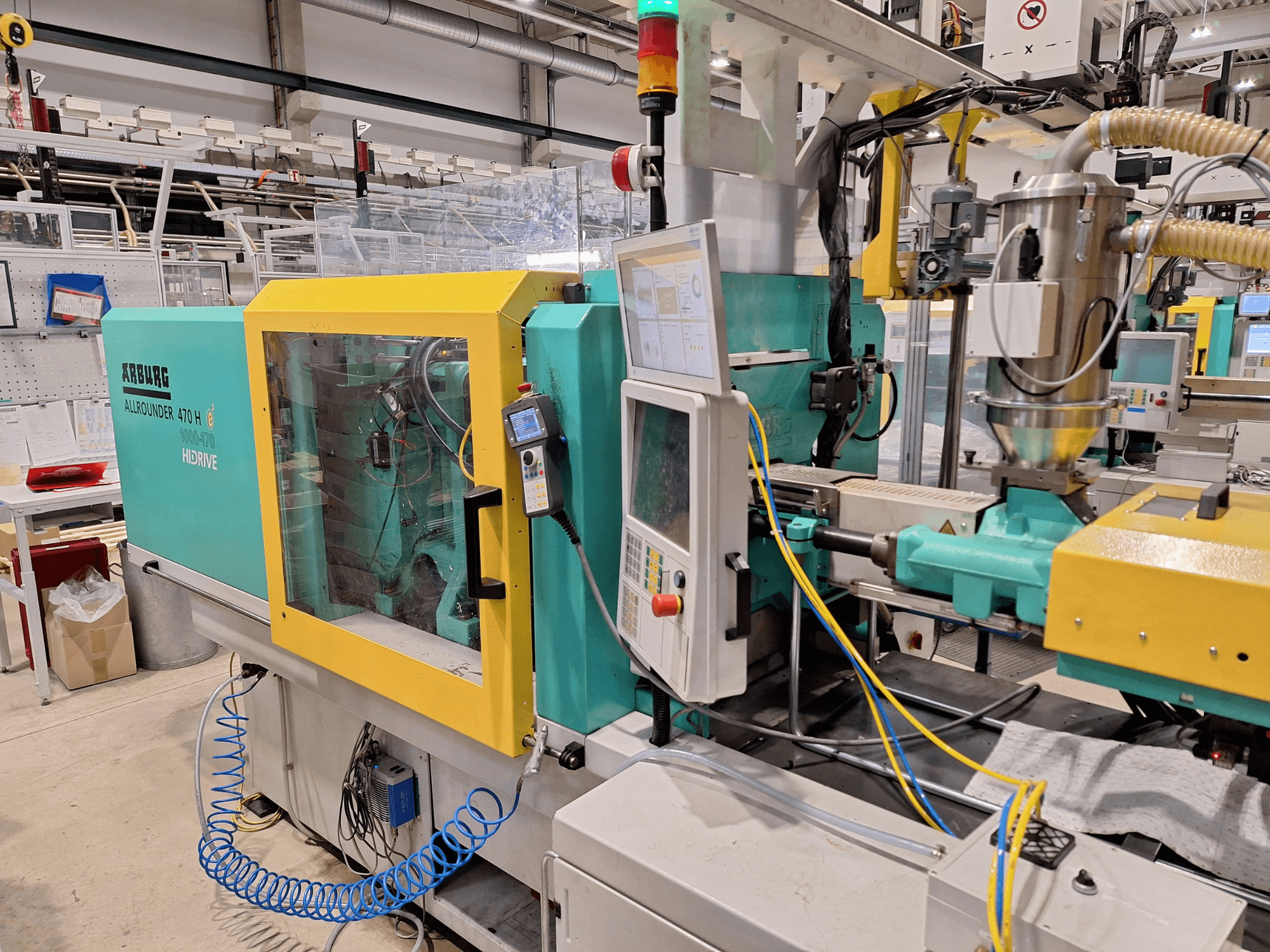 Arburg 470 H 1000-170 hydraulische spuitgietmachine, zijaanzicht bedieningspaneel en toevoersysteem.