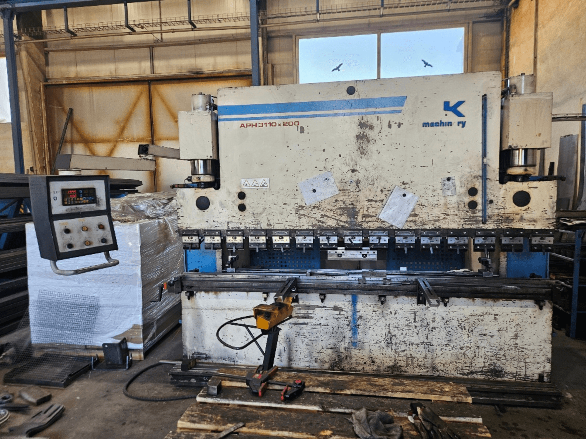 Baykal APH 3110x200 afkantpers in een werkplaats, vooraanzicht, met bedieningspaneel, metalen platen en gereedschappen zichtbaar.