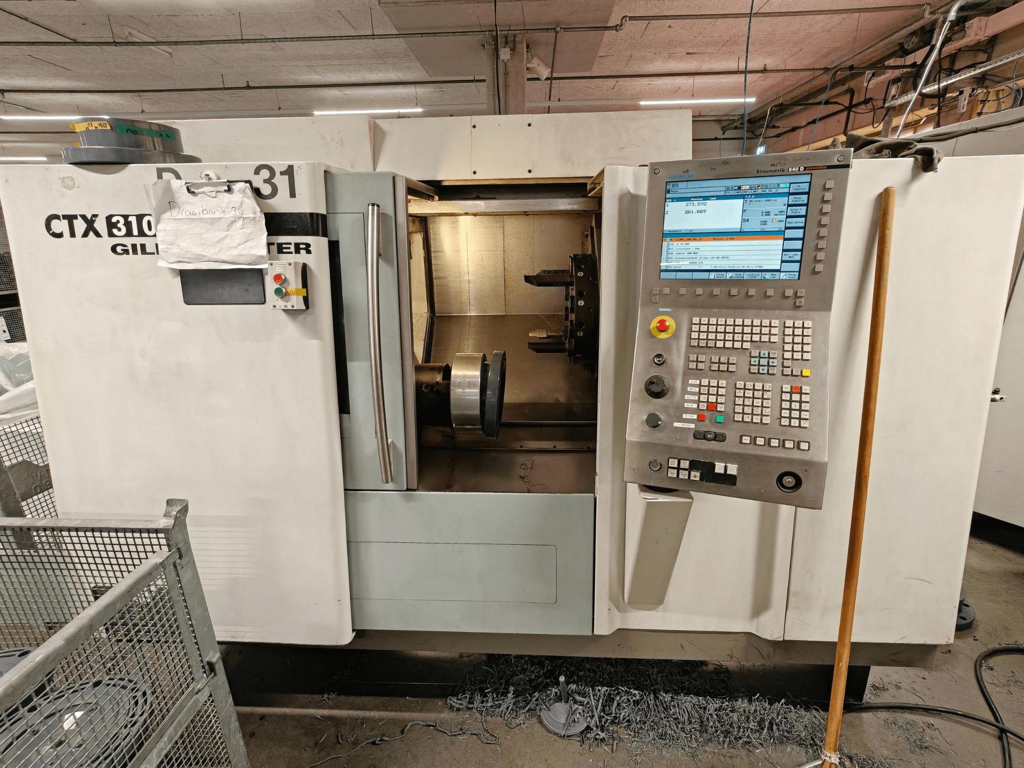 Gildemeister CTX 310 horizontale draaimachine, vooraanzicht met bedieningspaneel, toont gereedschappen en werkruimte binnenin.