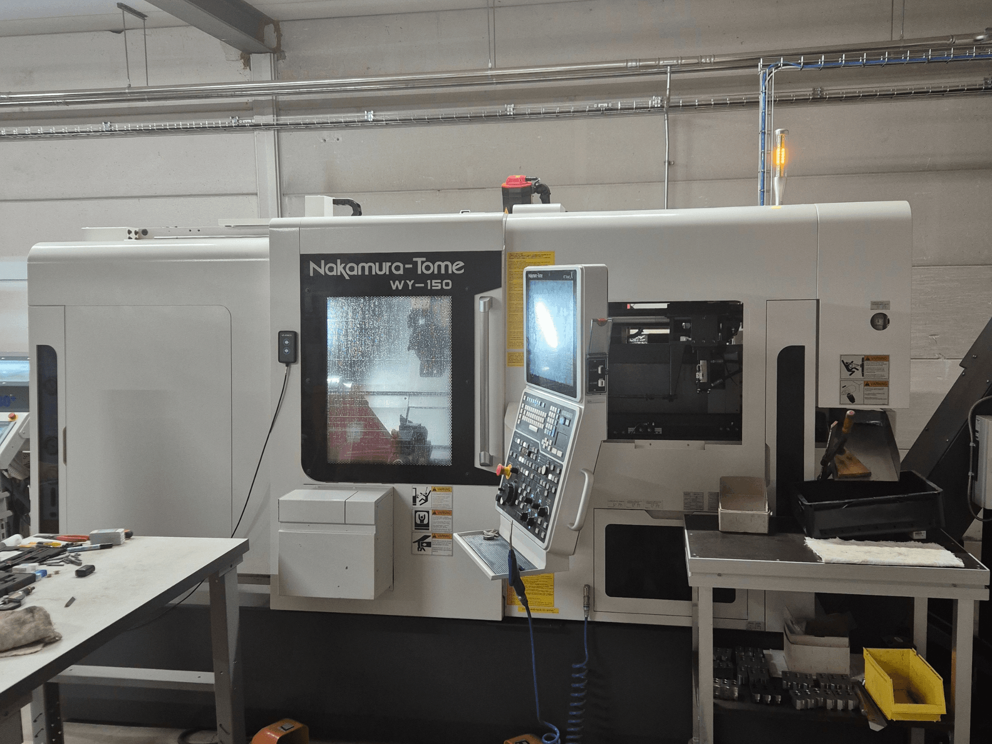 Nakamura-Tome WY-150 CNC draaibank in zijaanzicht, met bedieningspaneel, transparant venster en zichtbaar werkgebied.